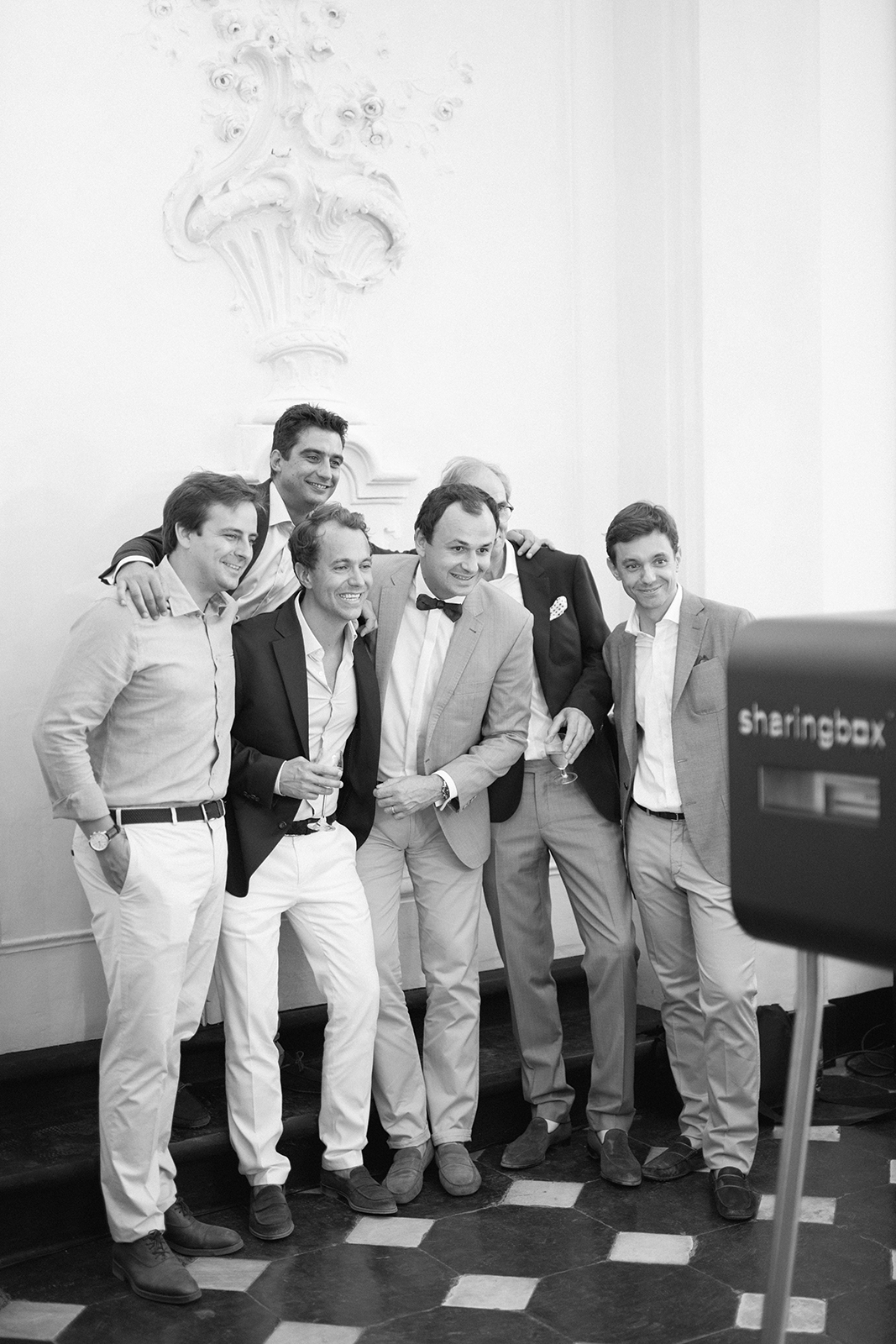 Black and white portrait of a group of men posing together and smiling during a wedding celebration