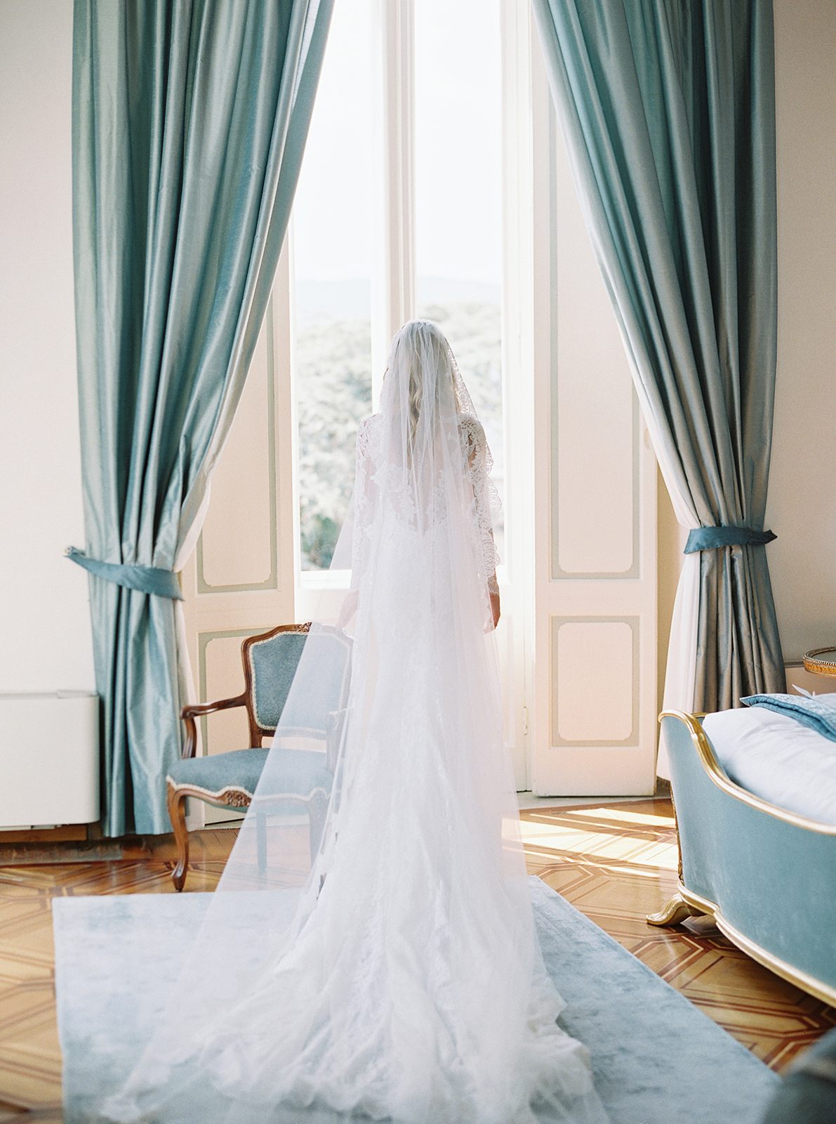 Bride standing by window in wedding dress during getting ready at Imperiale Palace Hotel in Portofino