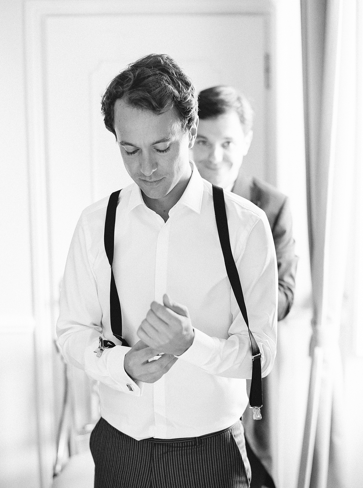 Black and white portrait of groom adjusting cufflinks at Imperiale Palace Hotel in Portofino