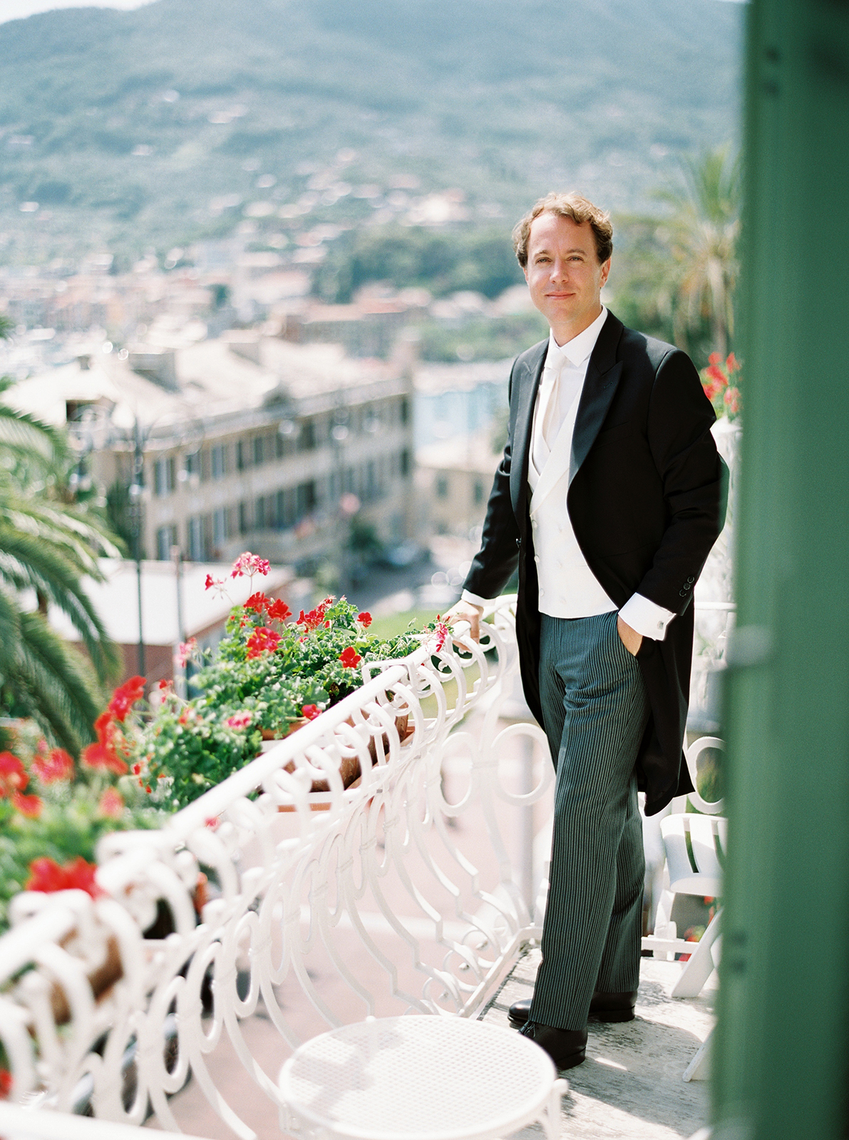 Groom standing on balcony at Imperiale Palace Hotel in Portofino with hillside view