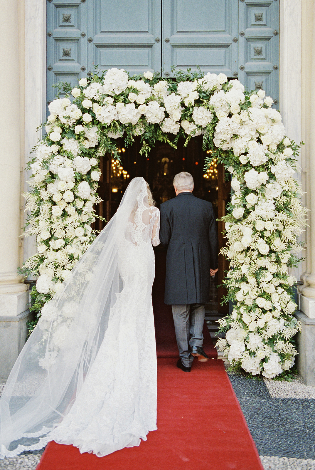 Bride walking with father through floral arch at Imperiale Palace Hotel in Portofino wedding