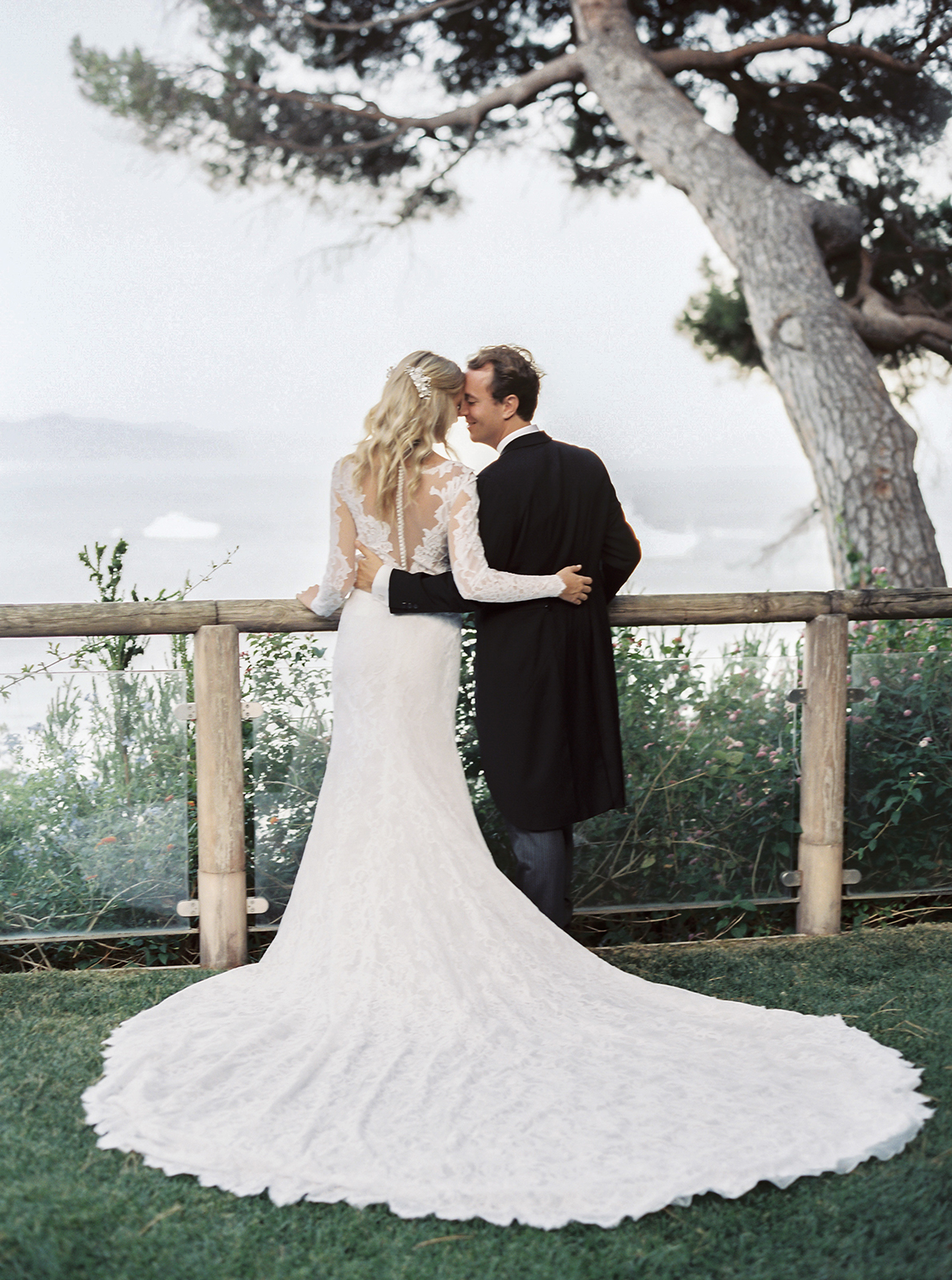 Bride and groom embracing by a railing with sweeping wedding dress train during a romantic portrait session in La Cervara in Portofino