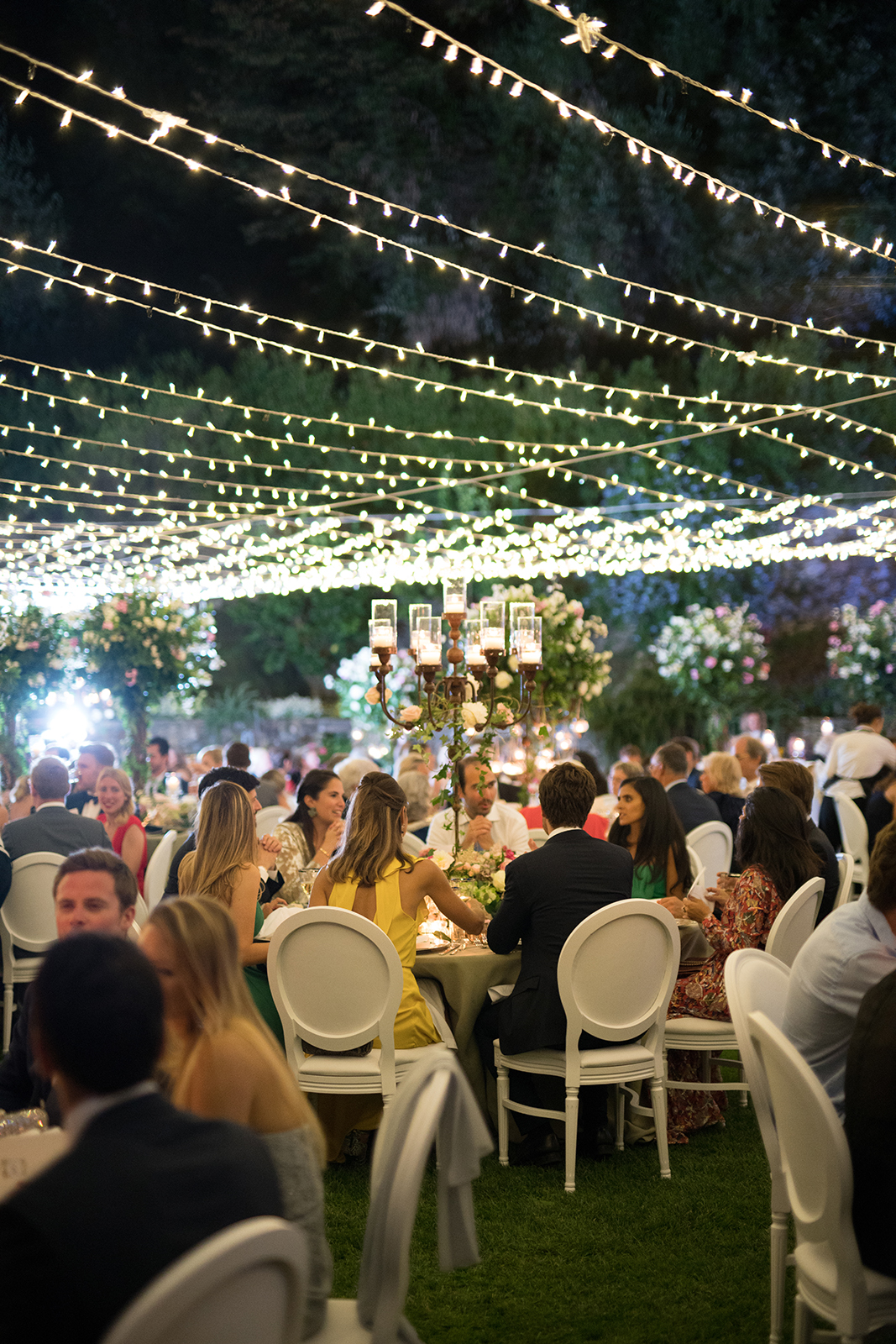 Romantic outdoor wedding reception at night with guests dining under warm string lights in La Cervara Portofino