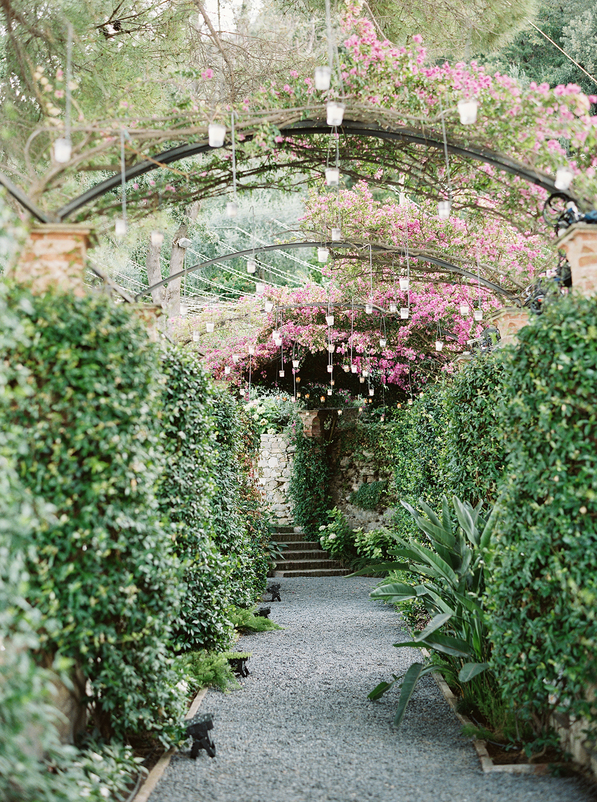 Romantic garden pathway at La Cervara Abbey wedding venue with pink florals and hanging lights in Portofino
