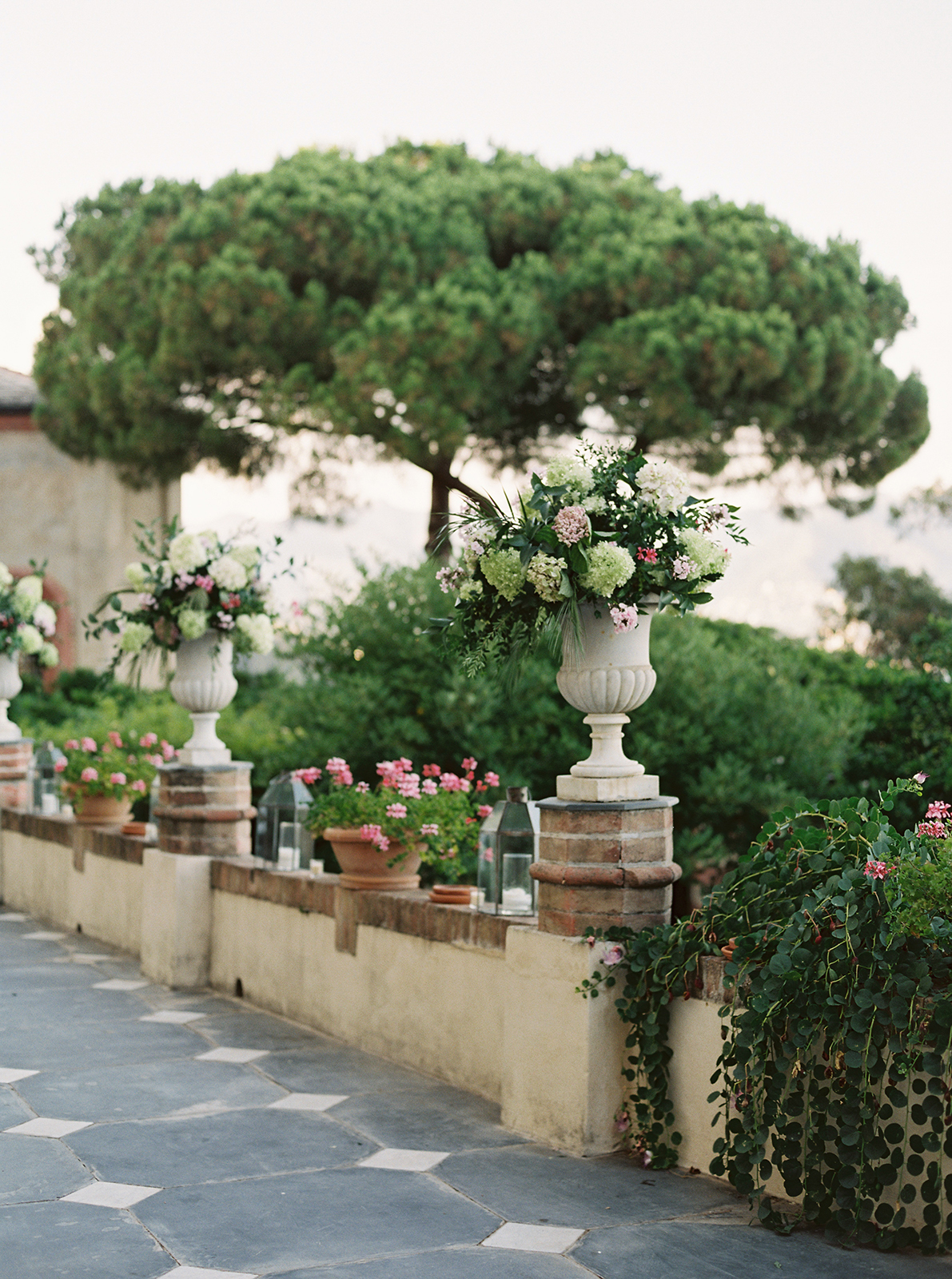 Floral arrangements lining the stone terrace at La Cervara Abbey in Portofino, overlooking lush gardens and the Ligurian coast