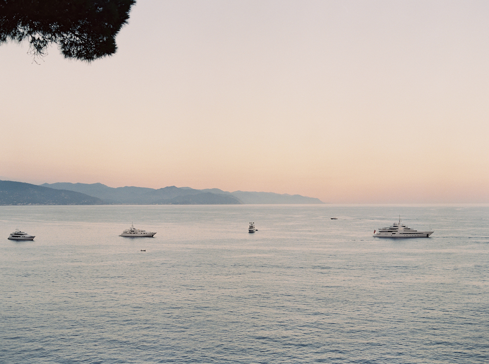 Luxury Italian Riviera seascape at sunset with yachts anchored on calm Mediterranean water