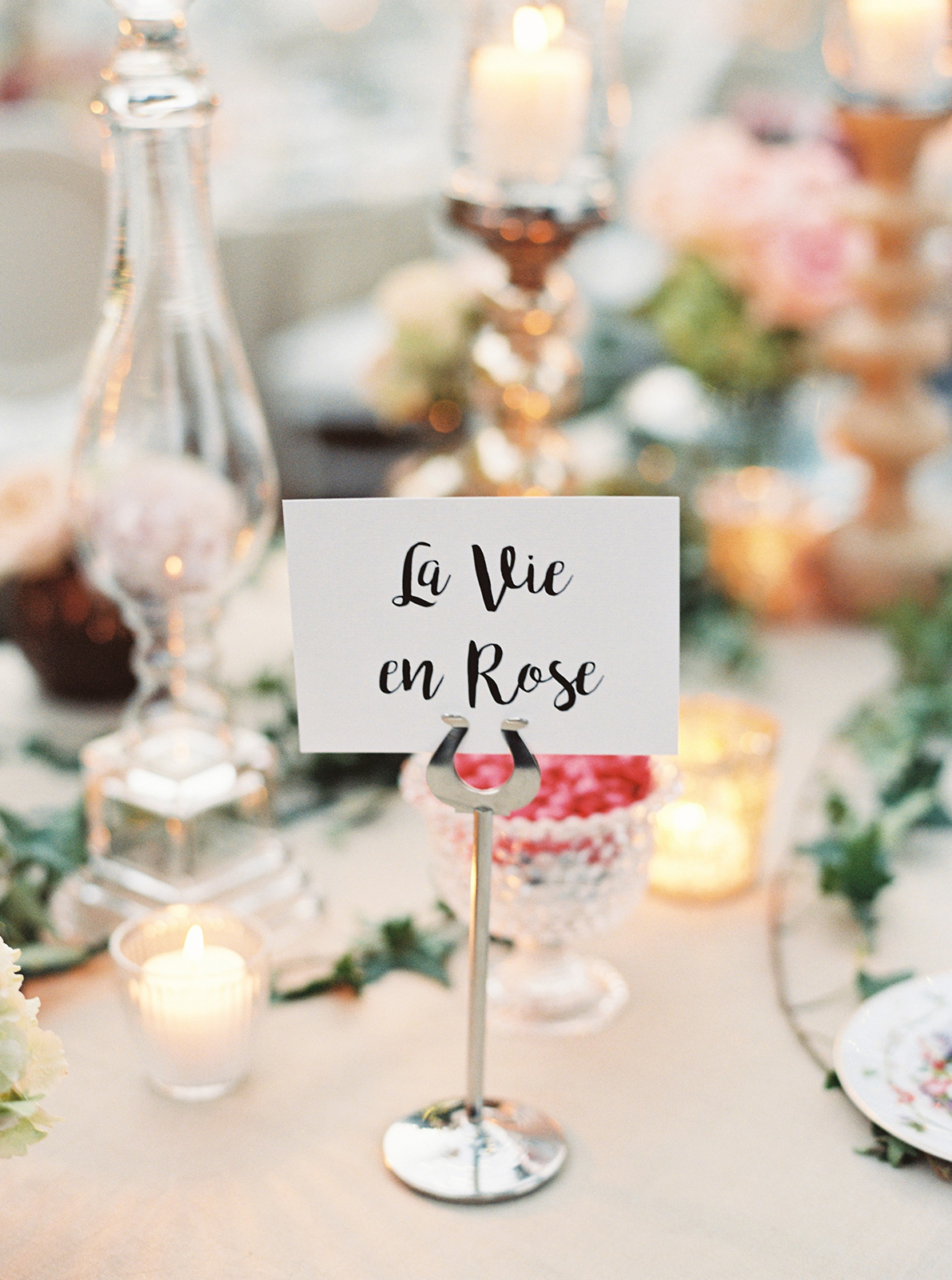 Intimate candlelit wedding table detail with elegant glassware, florals, and soft evening light