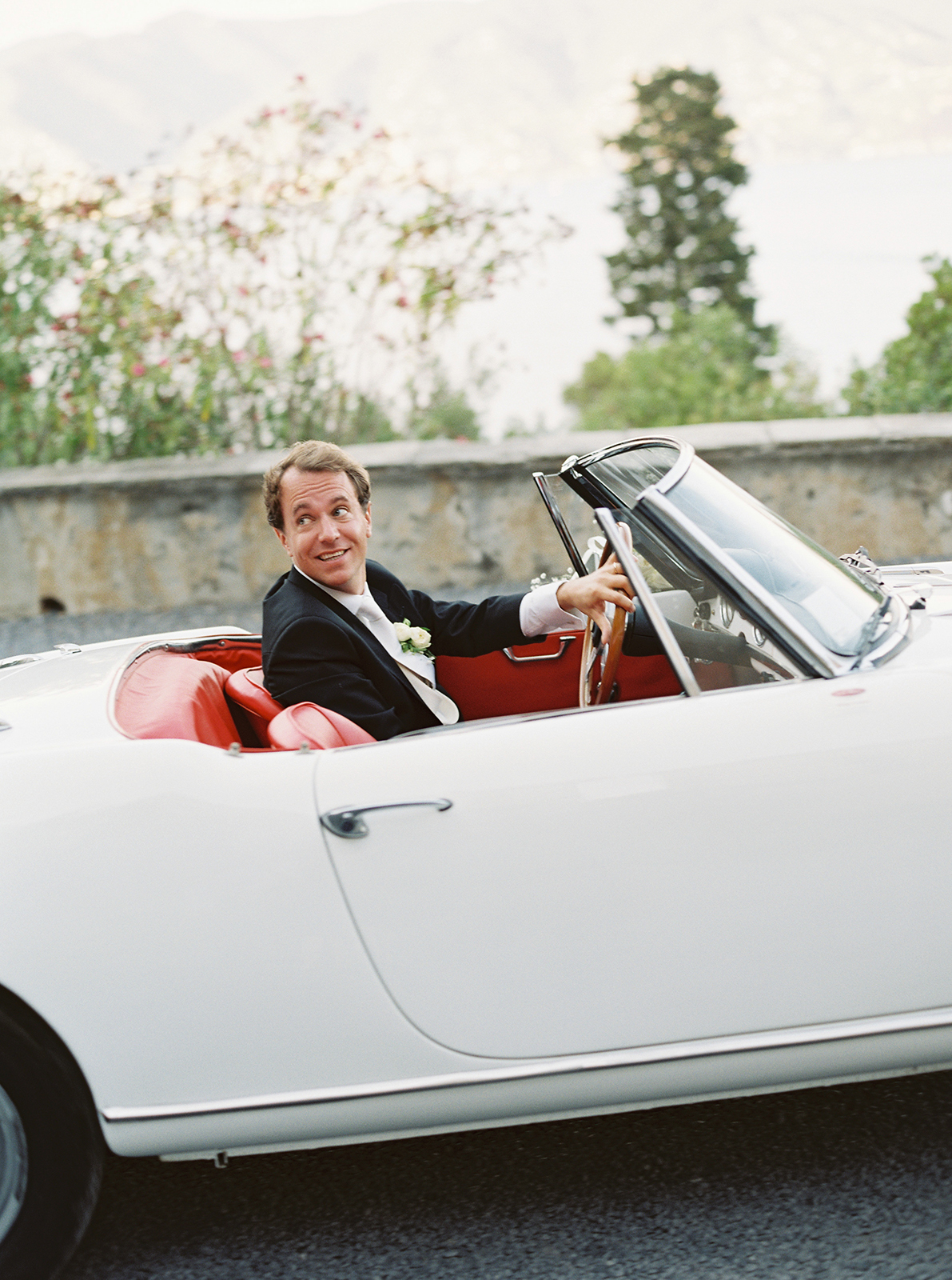 Groom arriving in vintage convertible for La Cervara Abbey wedding in Portofino