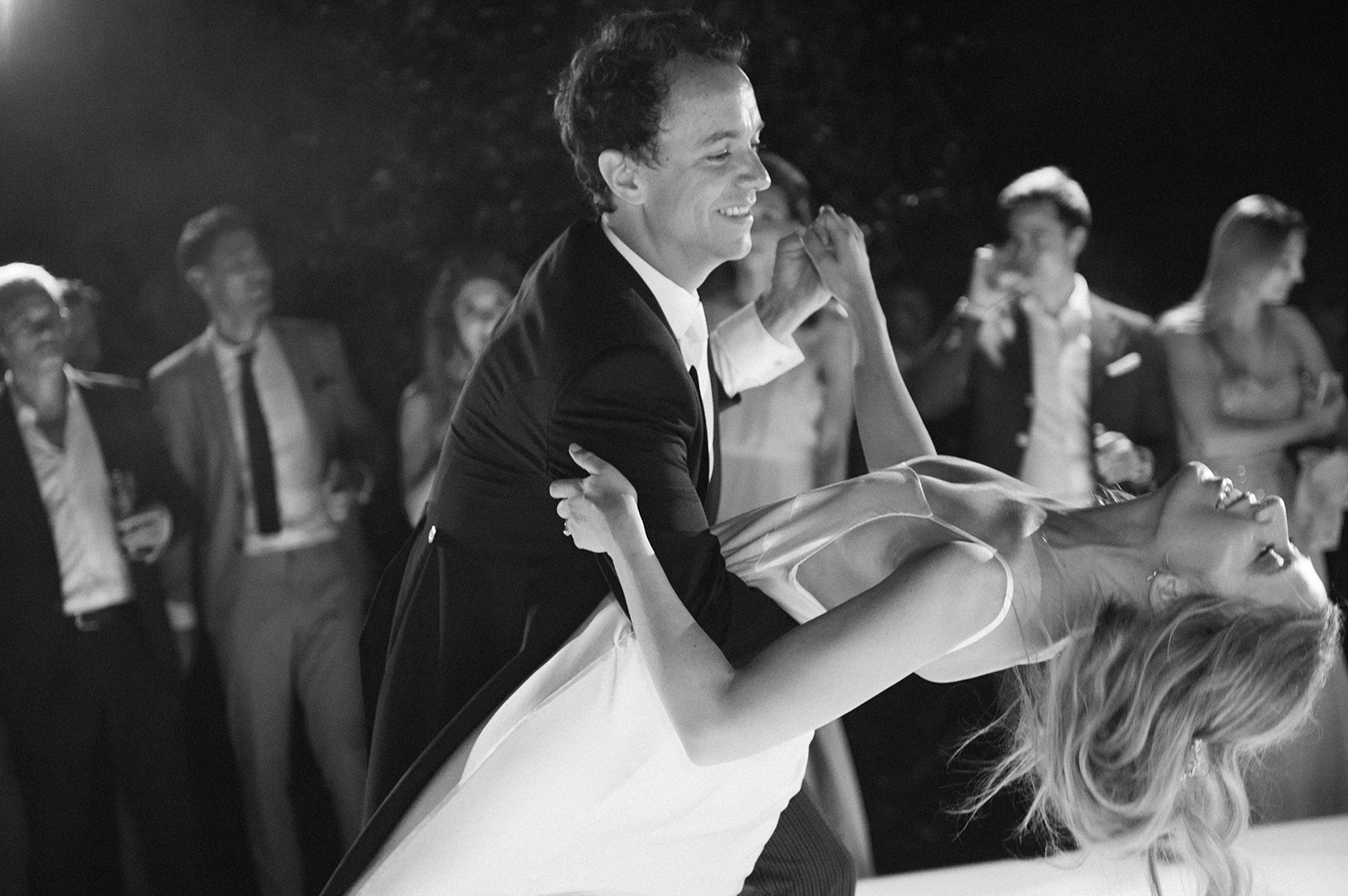 Black and white portrait of groom lifting bride during a joyful moment on the dance floor