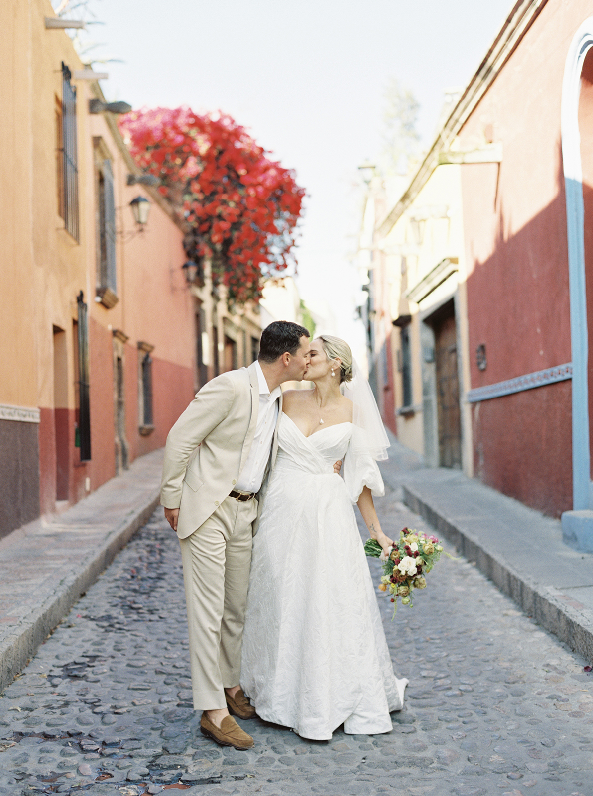 Wedding couple kissing on cobblestone street in San Miguel de Allende