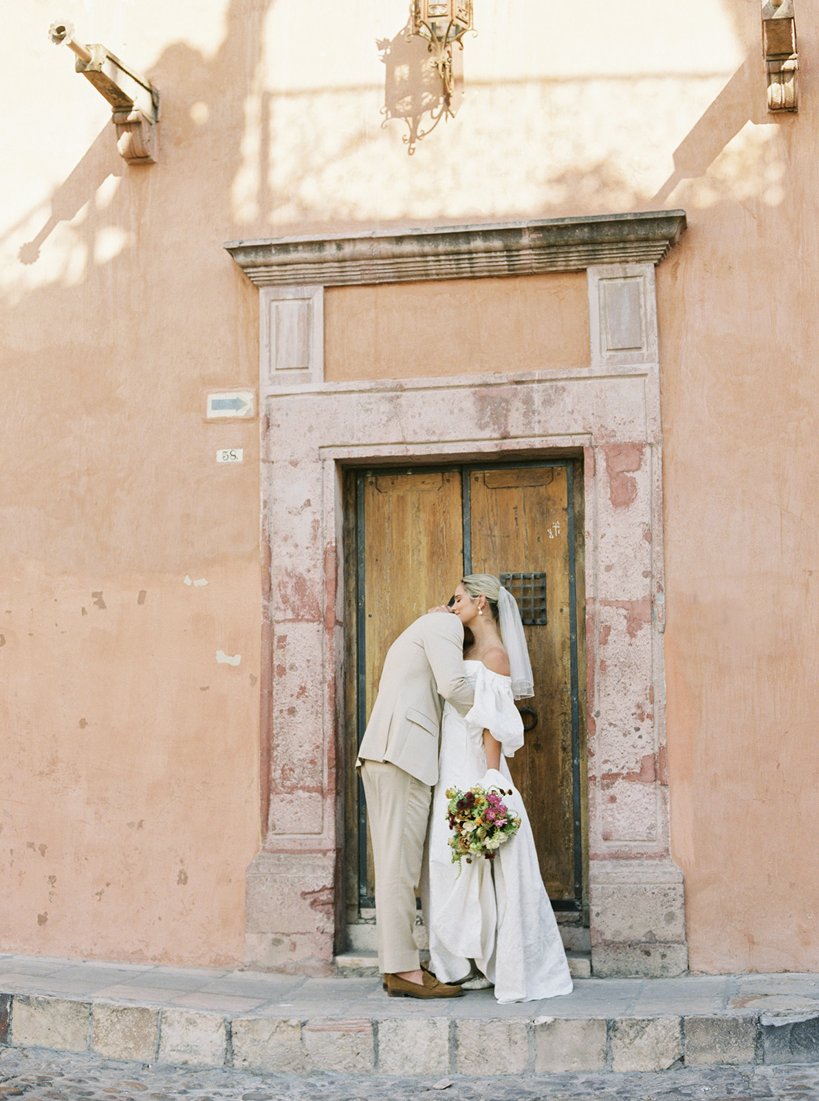 Wedding couple embracing outside historic doorway in San Miguel de Allende