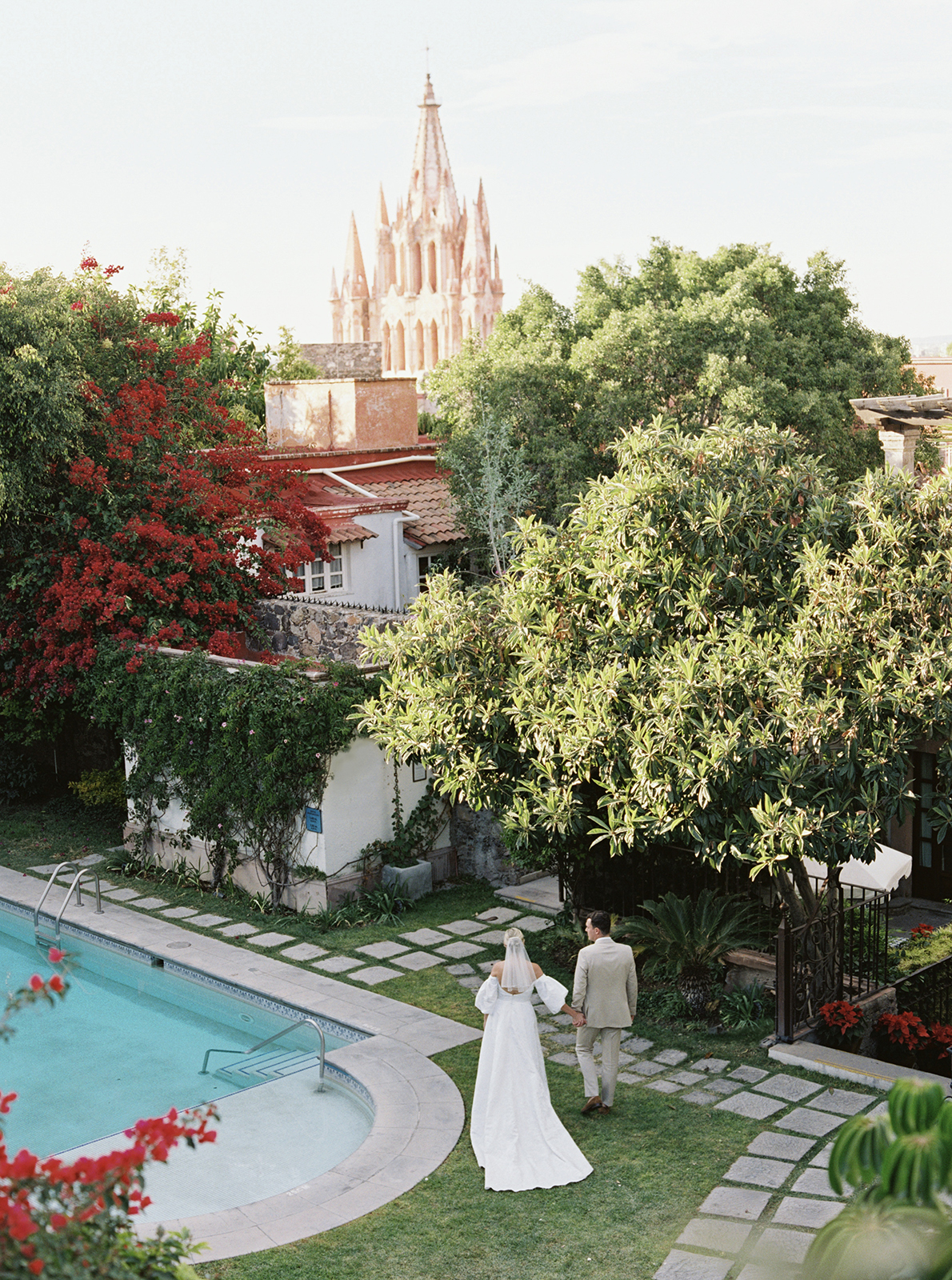 Wedding couple walking hand in hand through lush garden