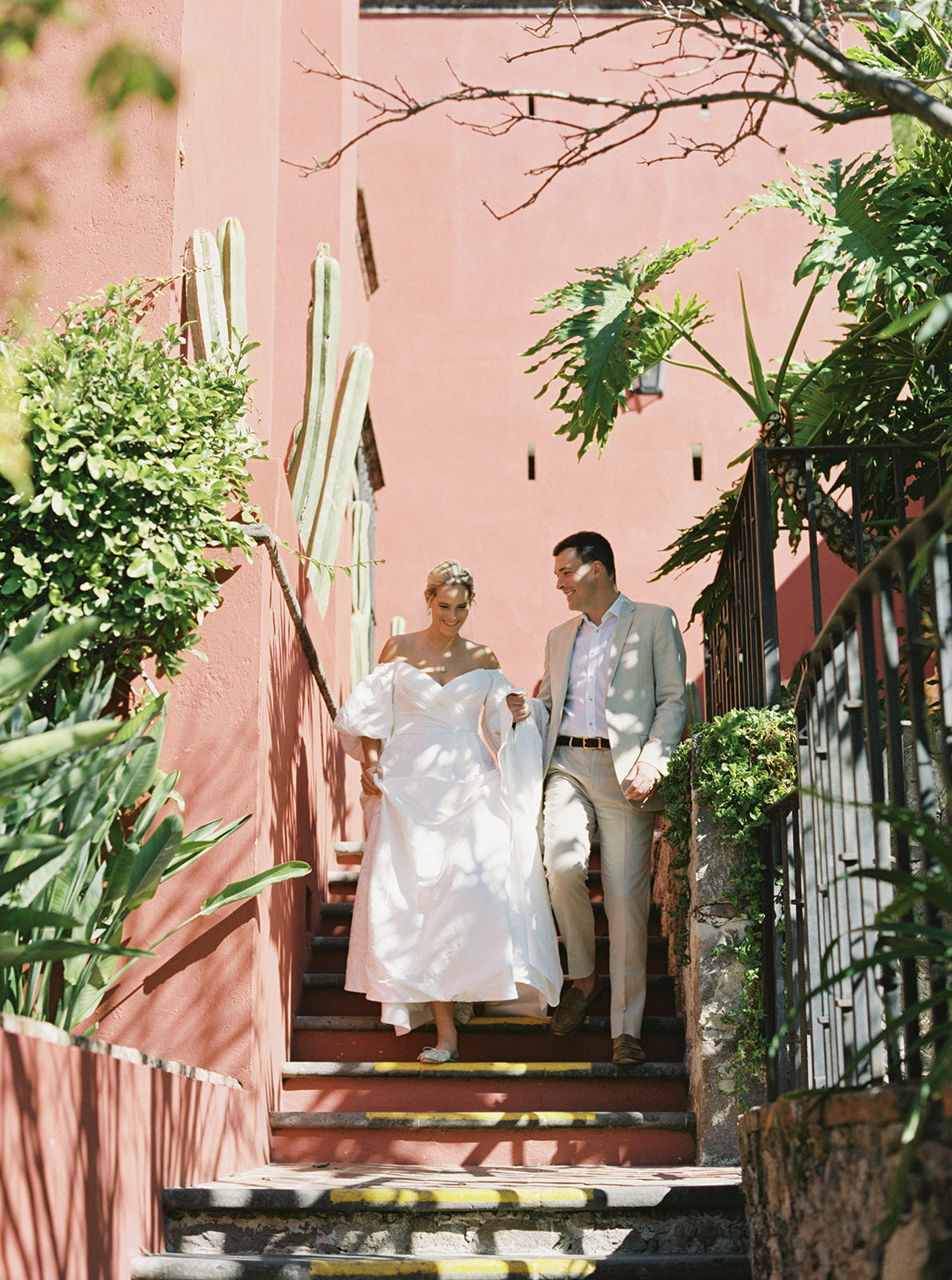bride and groom walking down the stairs into a lush garden