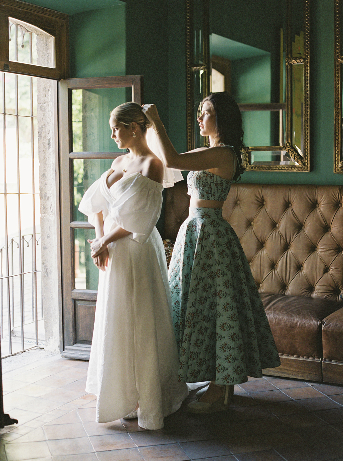 bride's friend helping bride adjust her veil