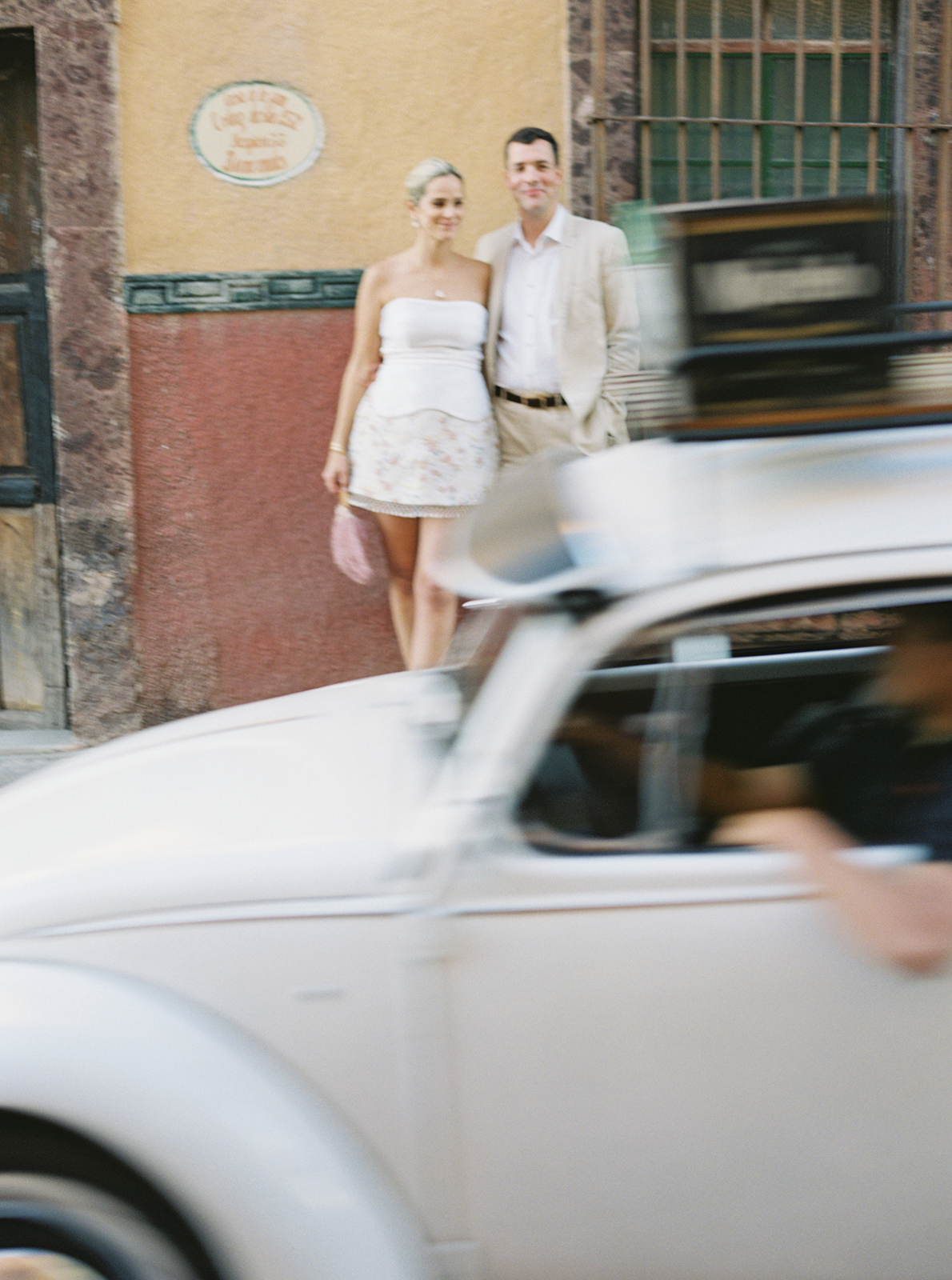 Wedding couple standing together as vintage car passes by