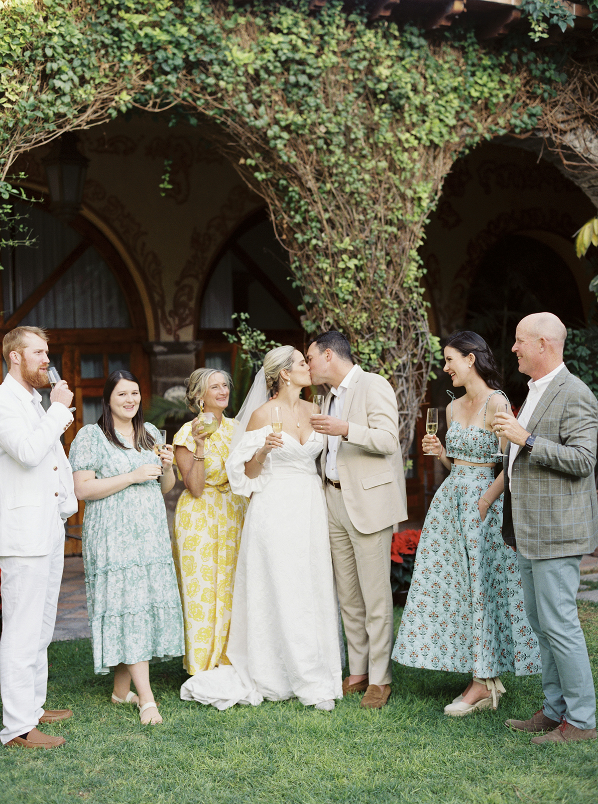 wedding guests cheering the couple with drink in their hand as the couple kisses