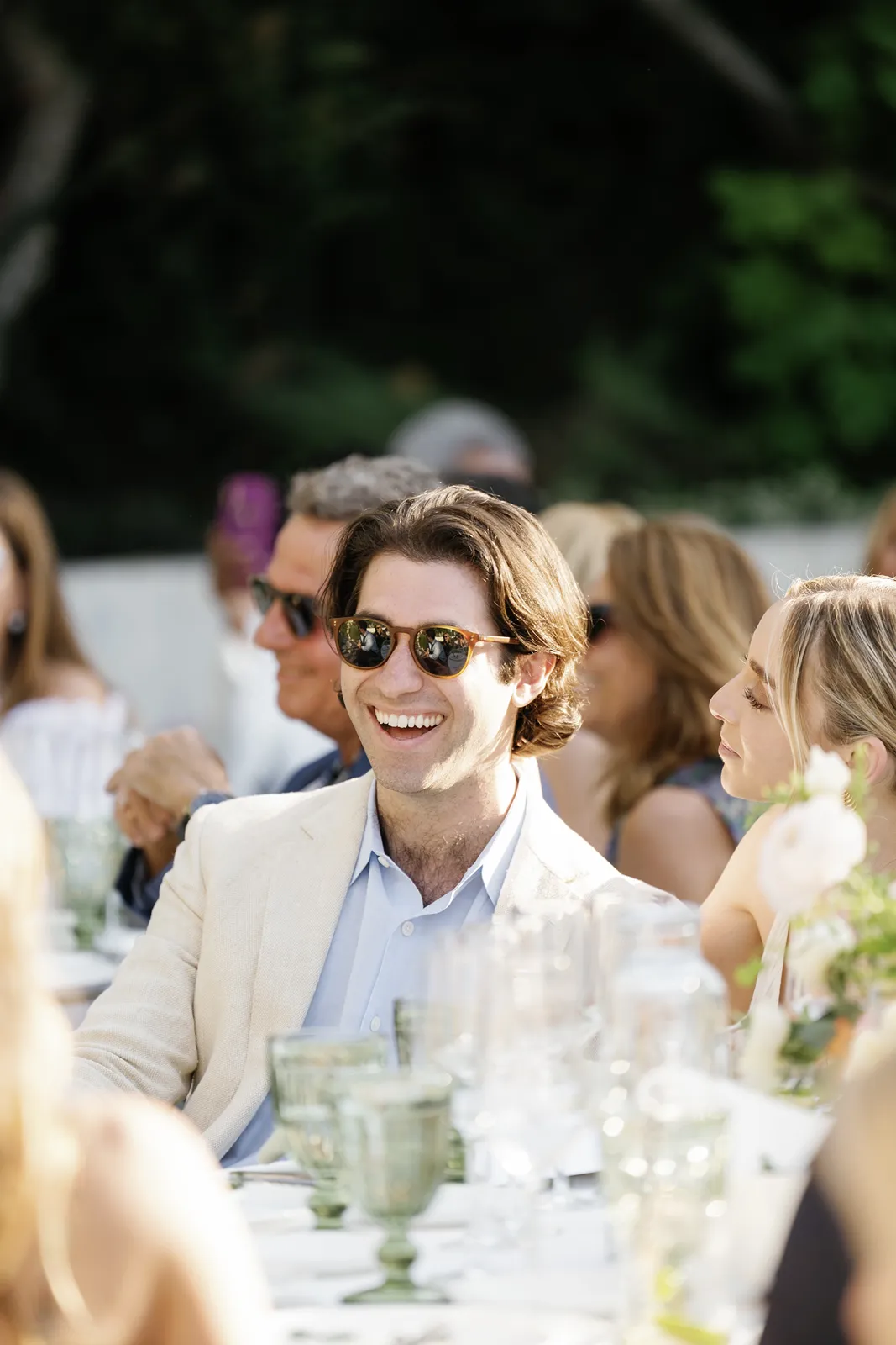 Groom laughing while seated at a dinner table during the rehearsal dinner