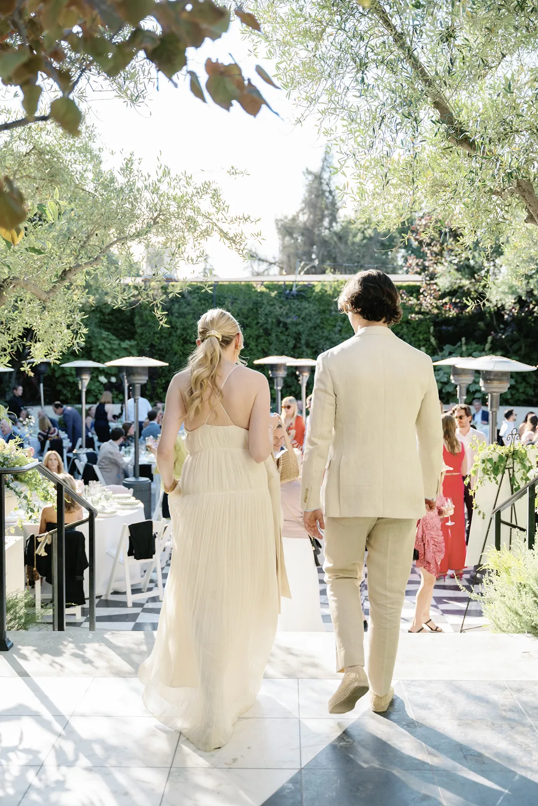 Bride and groom walking hand in hand toward guests at a rehearsal dinner