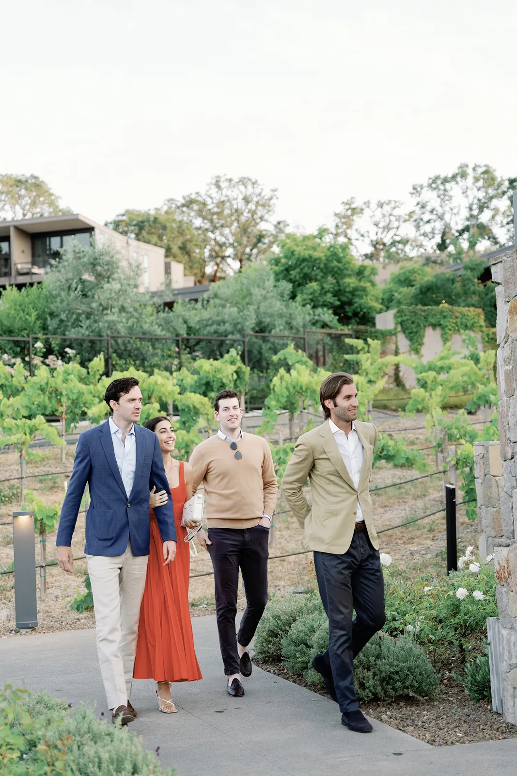 Friends walking through vineyards at a wine country rehearsal dinner