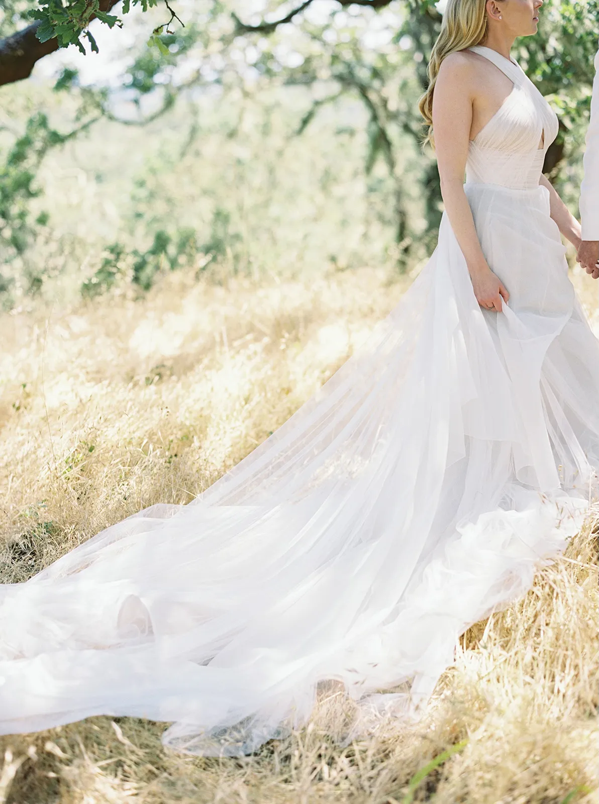 Close-up of the bride’s flowing white wedding gown trailing through the sunlit grass at Montage Healdsburg