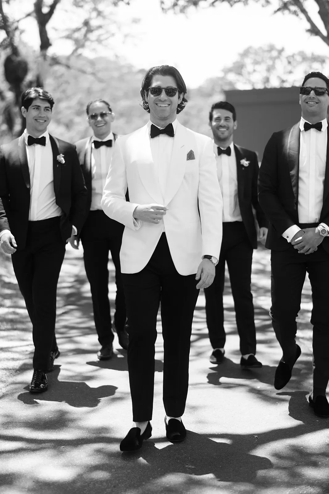 Groom and groomsmen walking together in classic tuxedos before the ceremony