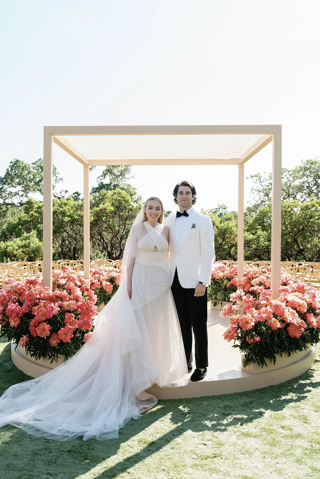 Bride and groom posing under the chuppah surrounded by lush pink flowers at their Montage Healdsburg wedding