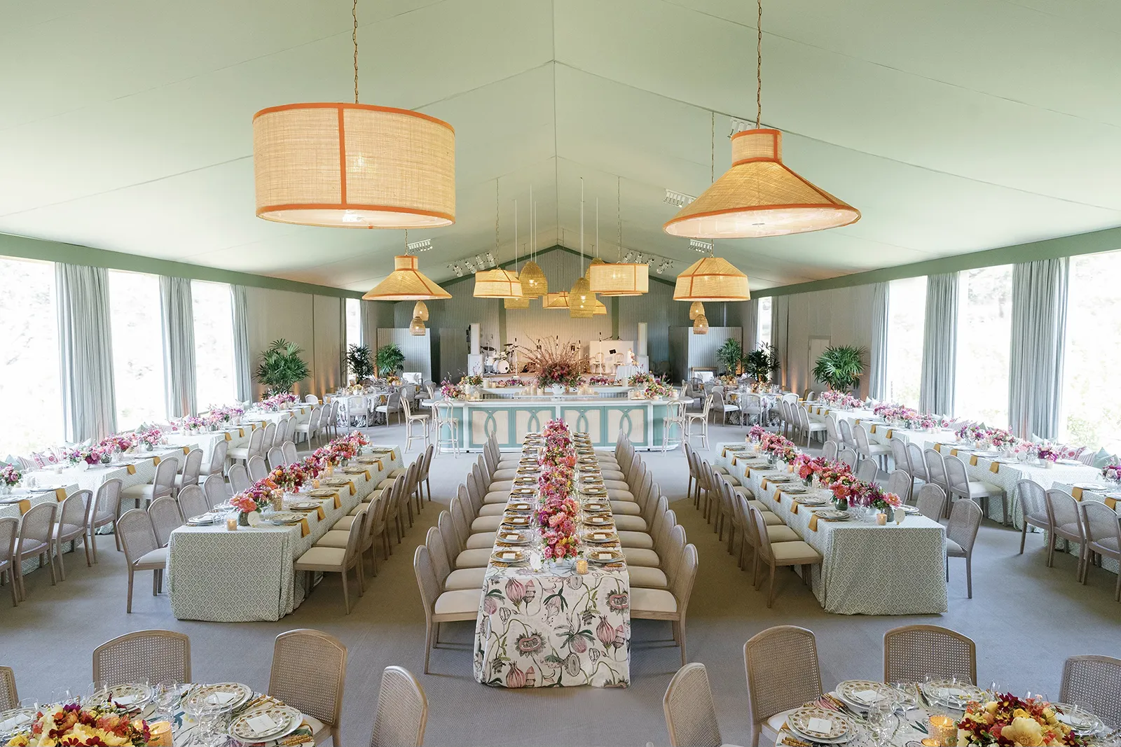 Wide view of an elegant wedding reception setup at Montage Healdsburg featuring long banquet tables, floral centerpieces, and woven pendant lights