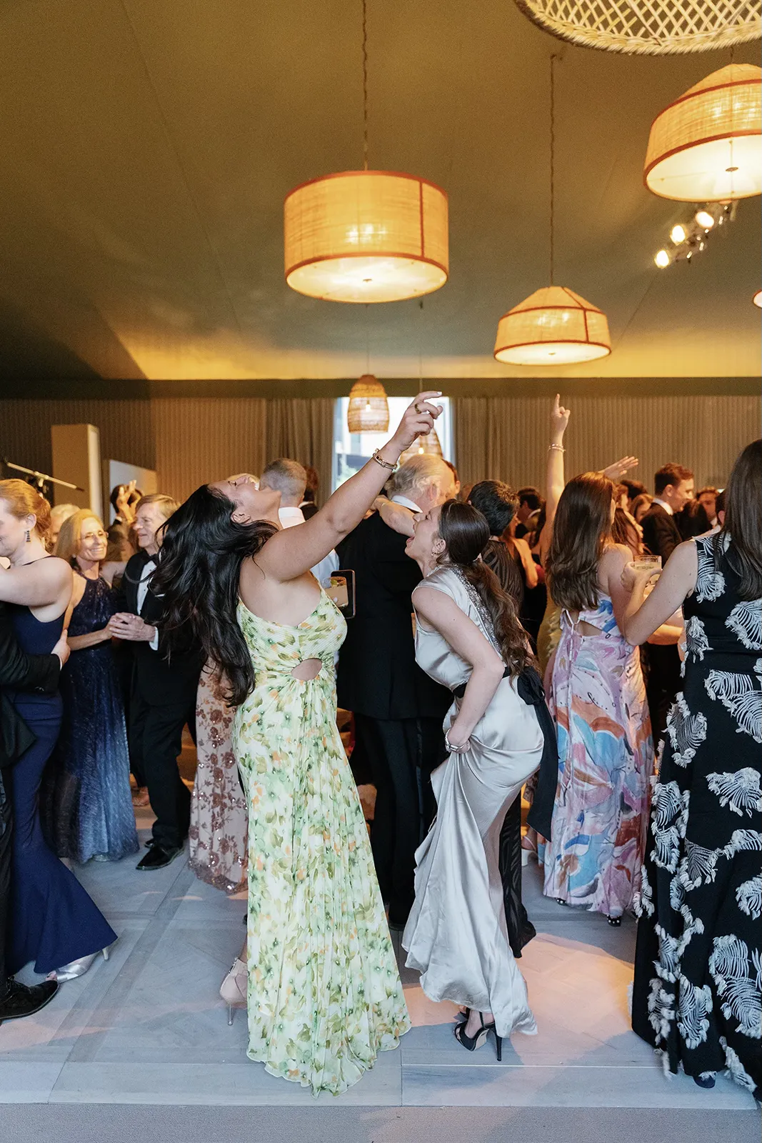 Wedding guests dancing and celebrating together during the reception with raised arms and joyful expressions