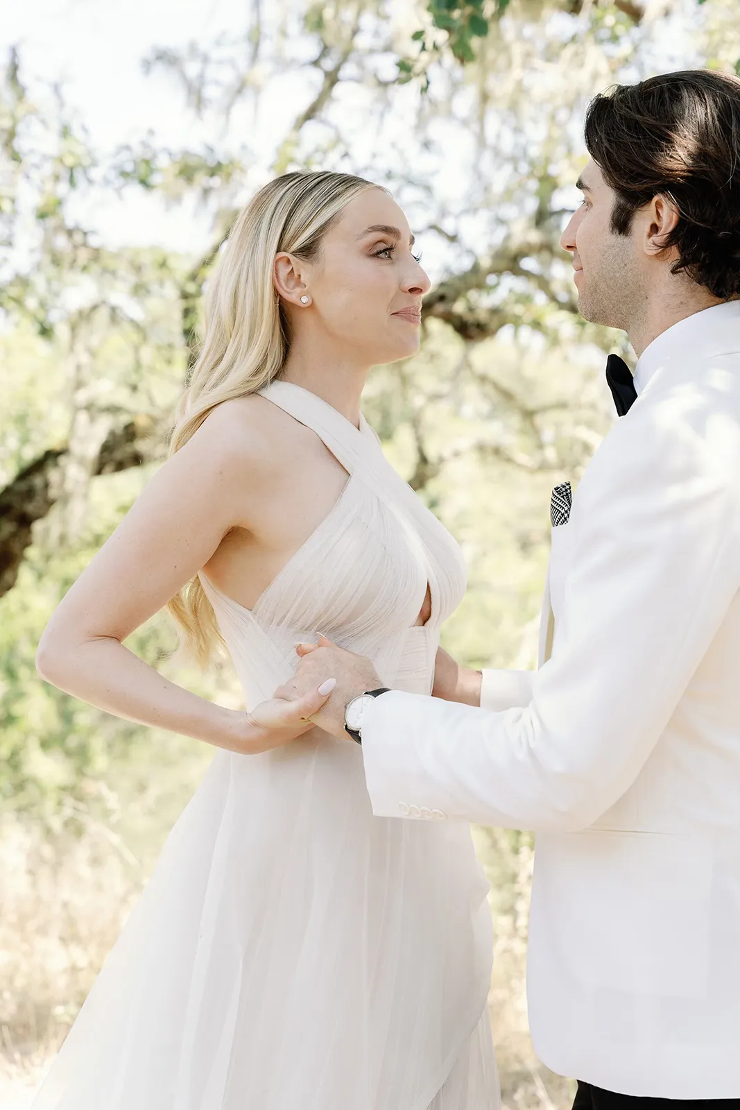 Bride and groom holding hands and facing each other during a quiet portrait moment outdoors