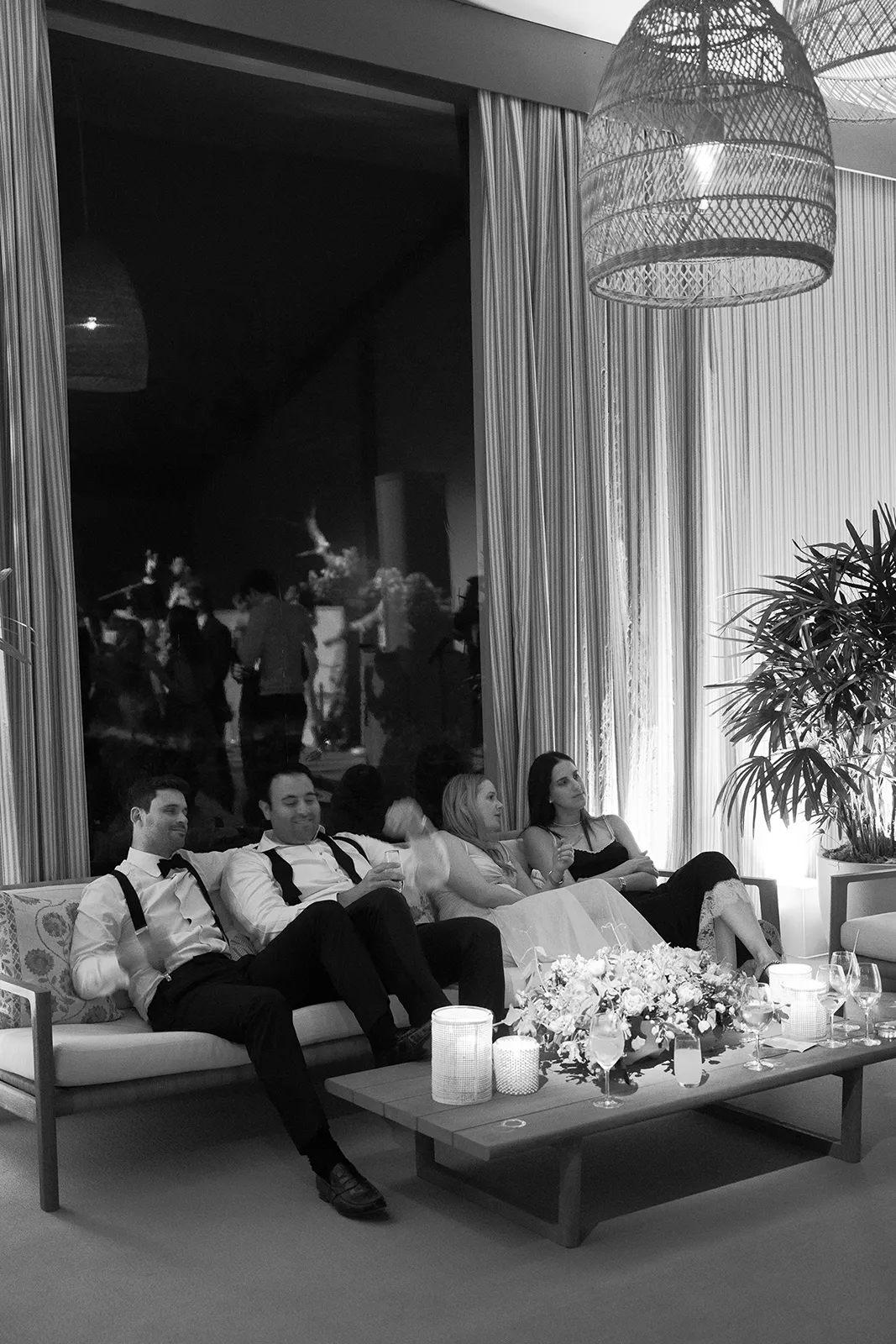 Wedding guests relaxing on lounge seating during the evening reception with candles and floral arrangements