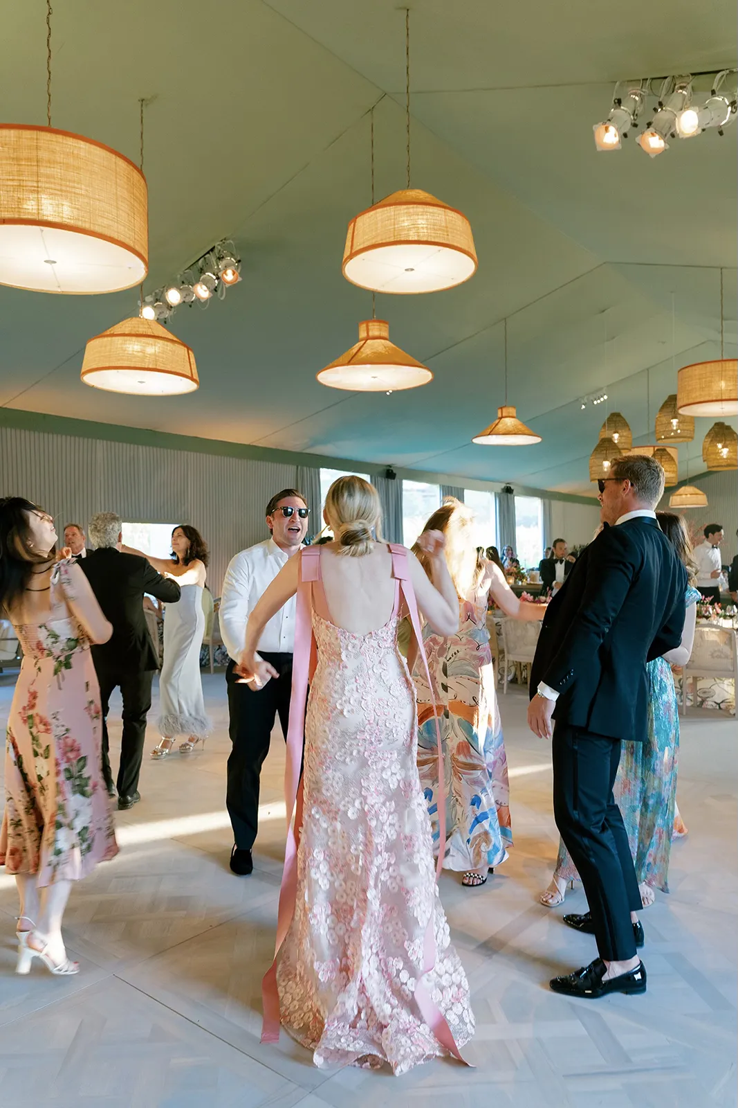 Wedding reception dancing with guests celebrating on the dance floor under woven pendant lights
