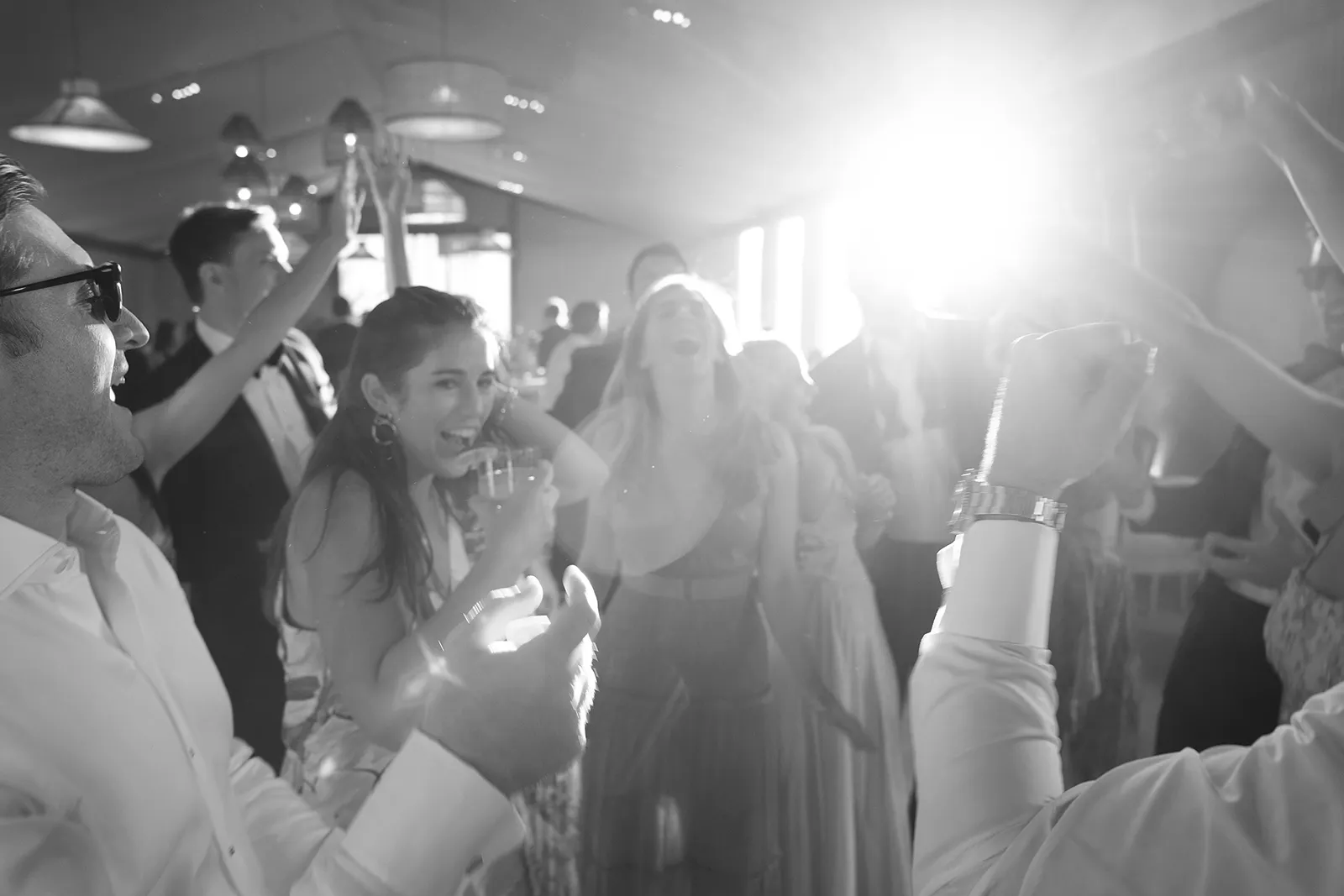 Wedding guests raising drinks and celebrating on the dance floor during a reception