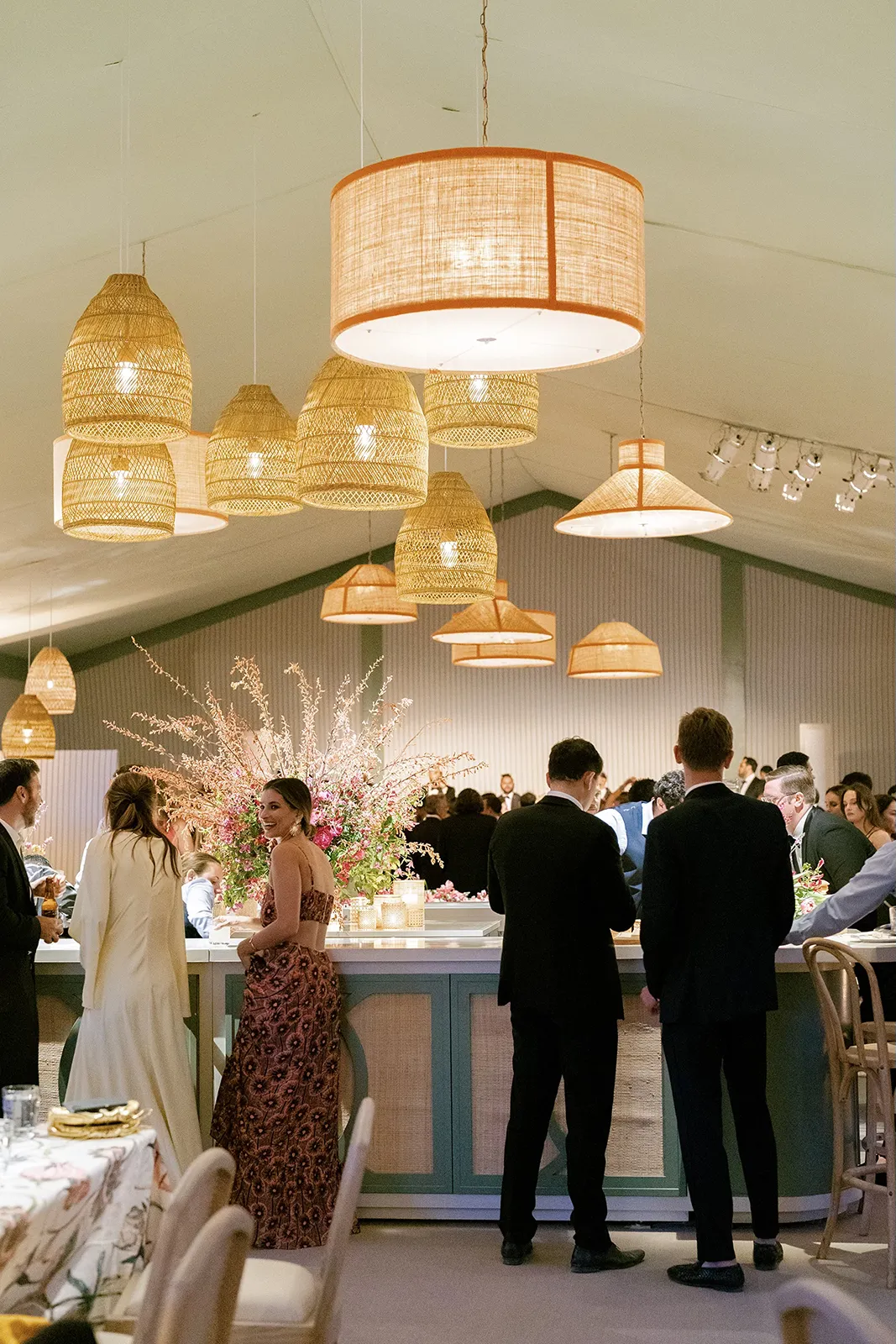Guests gather around a stylish wedding reception bar under woven pendant lights and floral arrangements in Montage Healdsburg