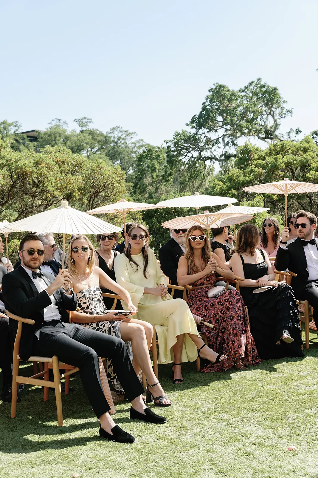 wedding guests seated with parasols waiting for ceremony to begin