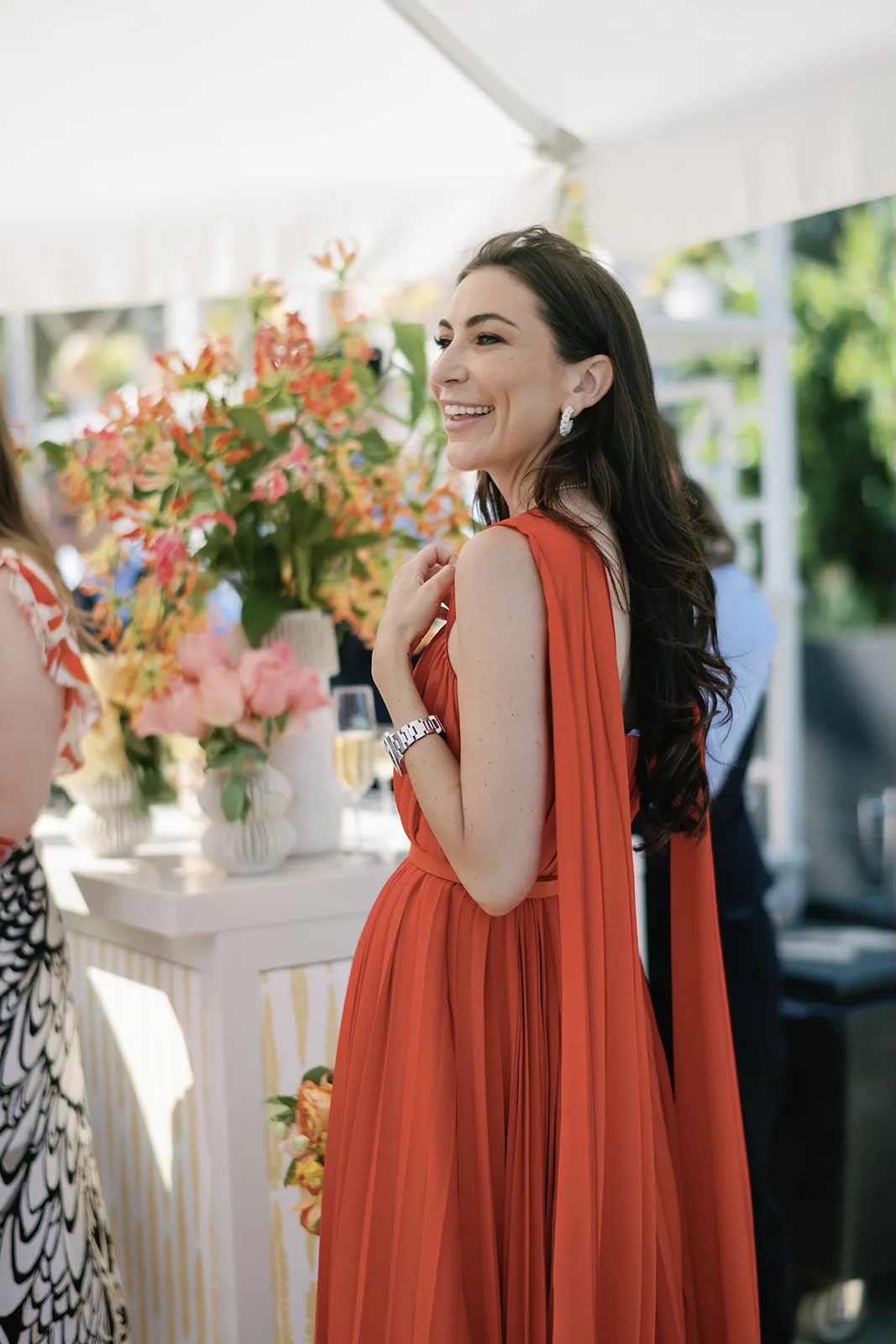 Wedding guest in a flowing rust-colored gown smiling near the reception bar at a Montage Healdsburg wedding