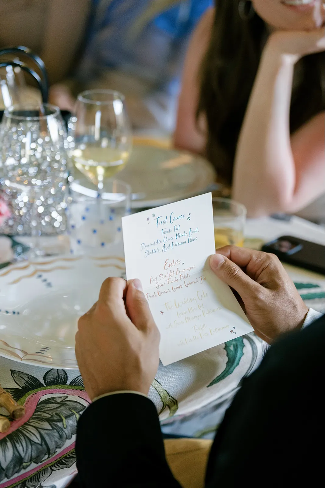 Wedding guest reading a custom dinner menu at a thoughtfully styled