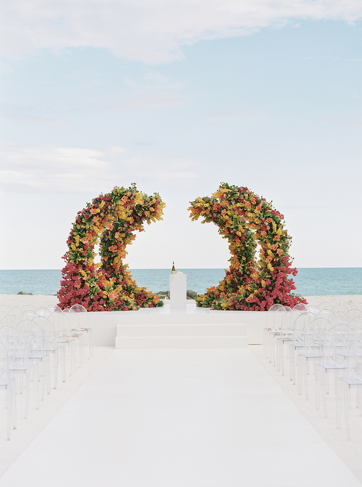 Oceanfront wedding ceremony at Faena Hotel Miami Beach featuring sculptural floral arches and white aisle seating