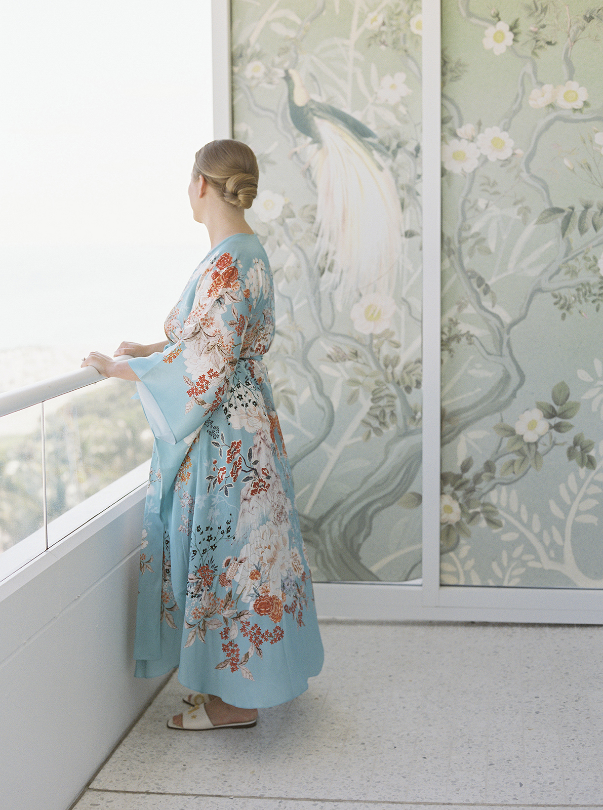 bride wearing silk robe overlooking suite balcony before ceremony