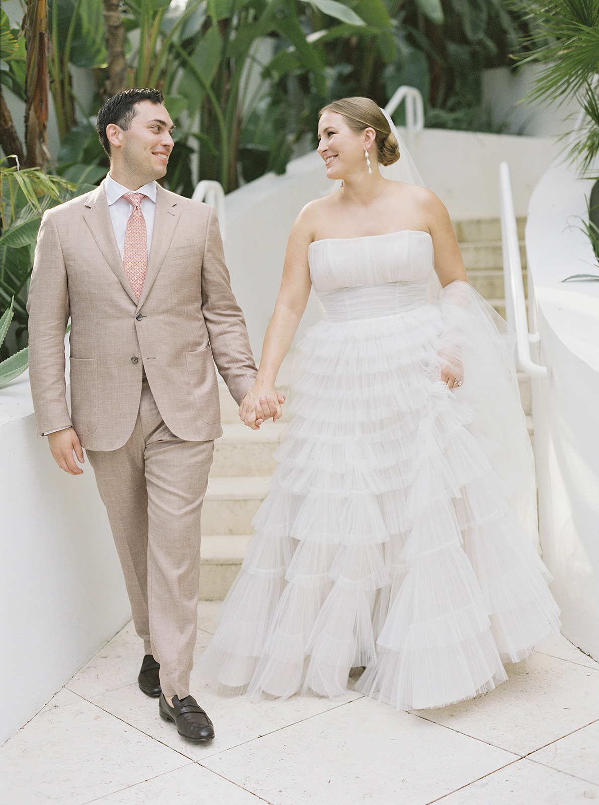 Bride and groom holding hands while walking through Faena Hotel Miami Beach gardens