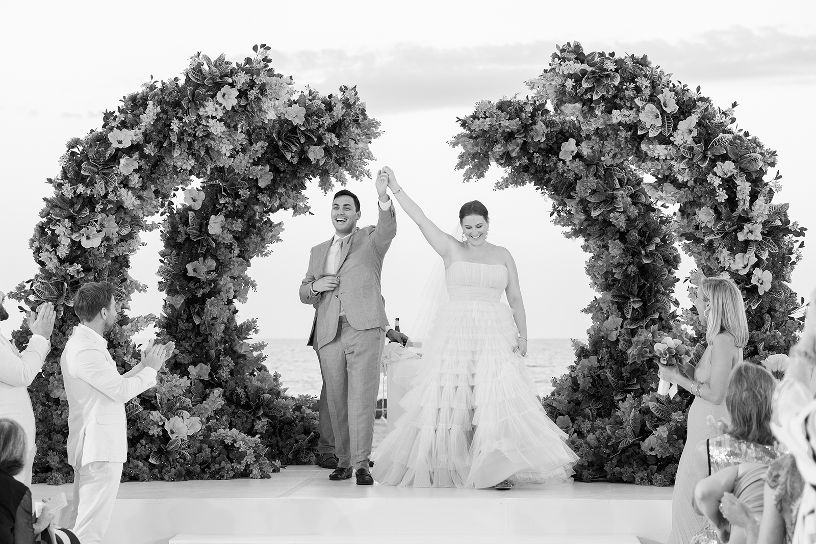 Bride and groom raising their hands in celebration as they walk back down the aisle