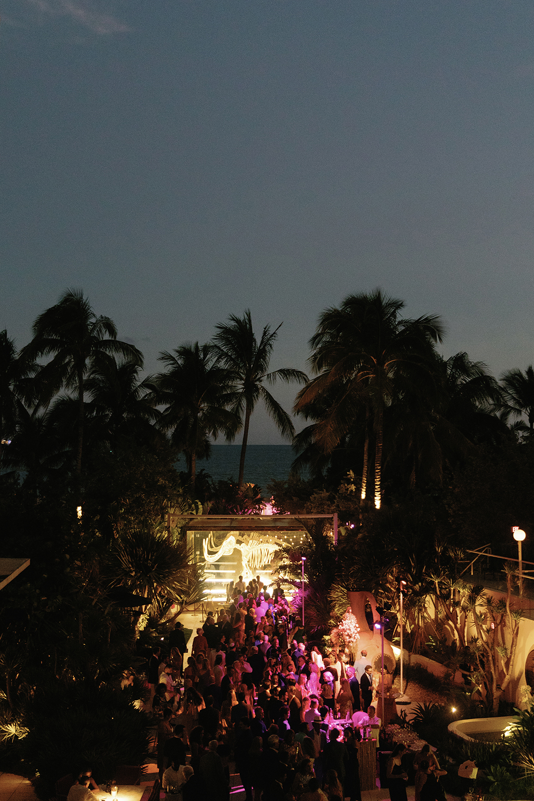 Overhead view of a lively outdoor cocktail hour at night with guests mingling