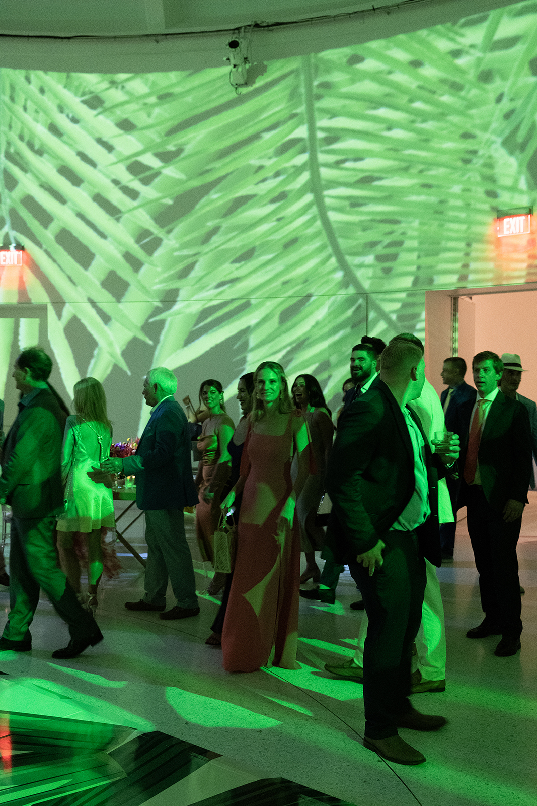 Wedding guests dancing together under dramatic green lighting during the reception