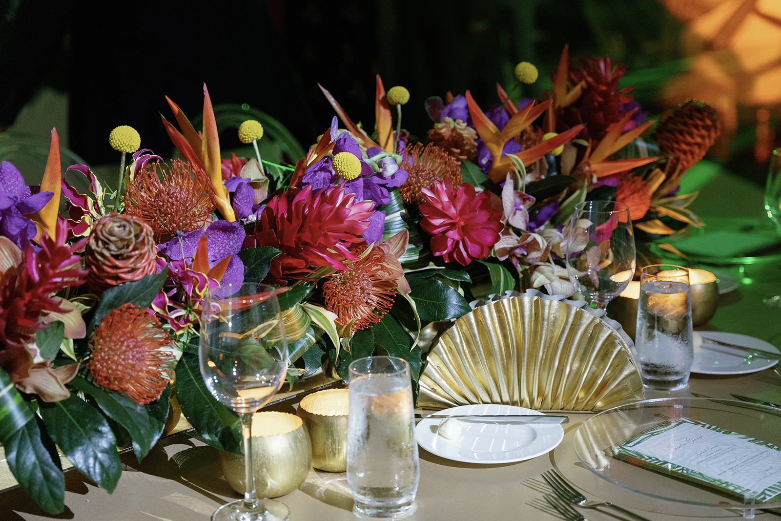 Close-up of a lush floral centerpiece with candles and elegant place settings at a wedding reception