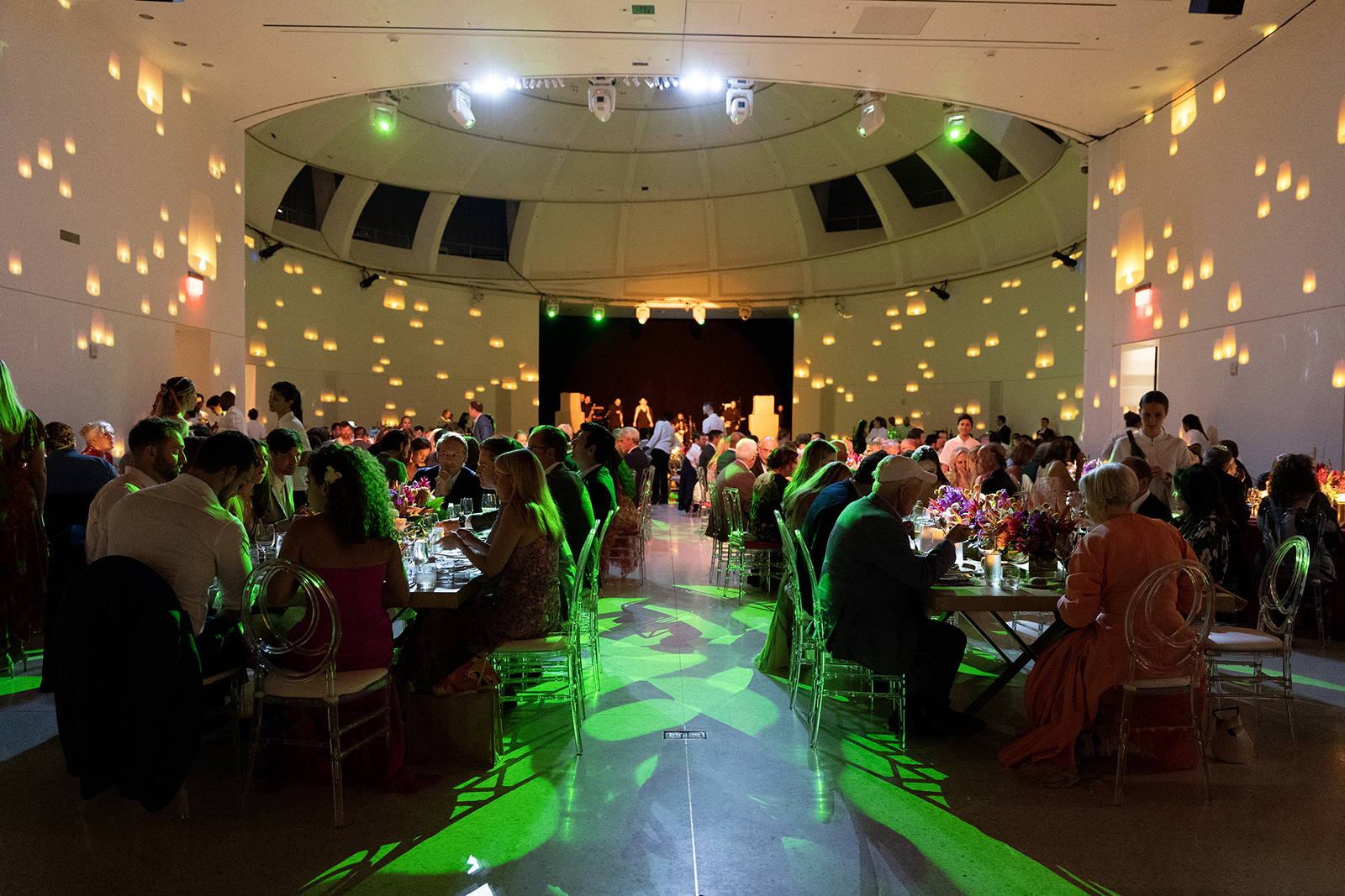 Wide view of a Faena Miami Beach wedding reception with long dinner tables, glowing candles, and seated guests.