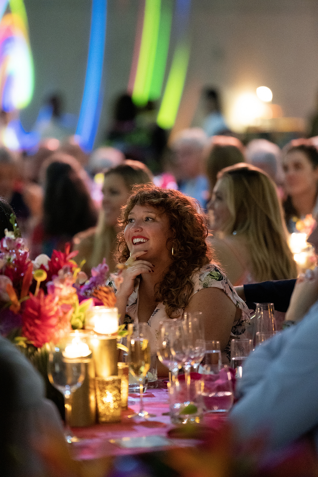 Wedding guest smiling during heartfelt reception speech, surrounded by candlelight and vibrant florals