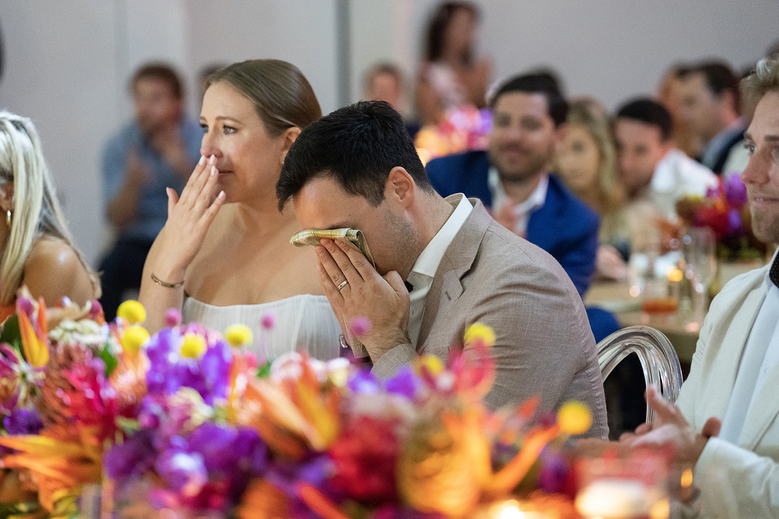 Bride and groom wiping away tears during emotional wedding toasts at the reception