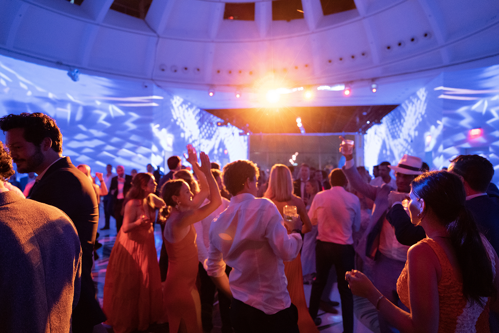 Dance floor filled with wedding guests celebrating under colorful lighting and energetic atmosphere