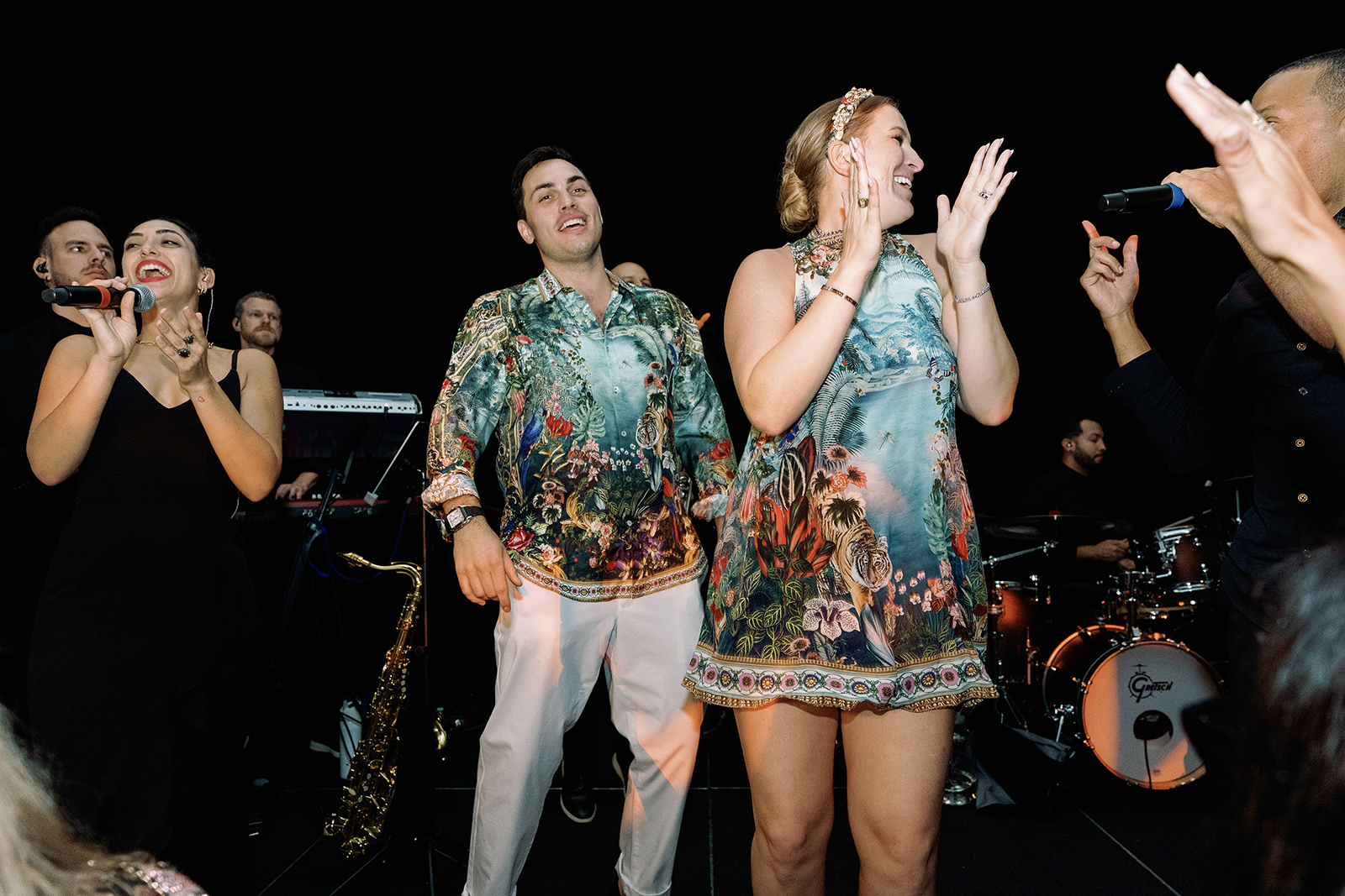 Bride and groom dancing on stage with live band during high-energy wedding reception performance