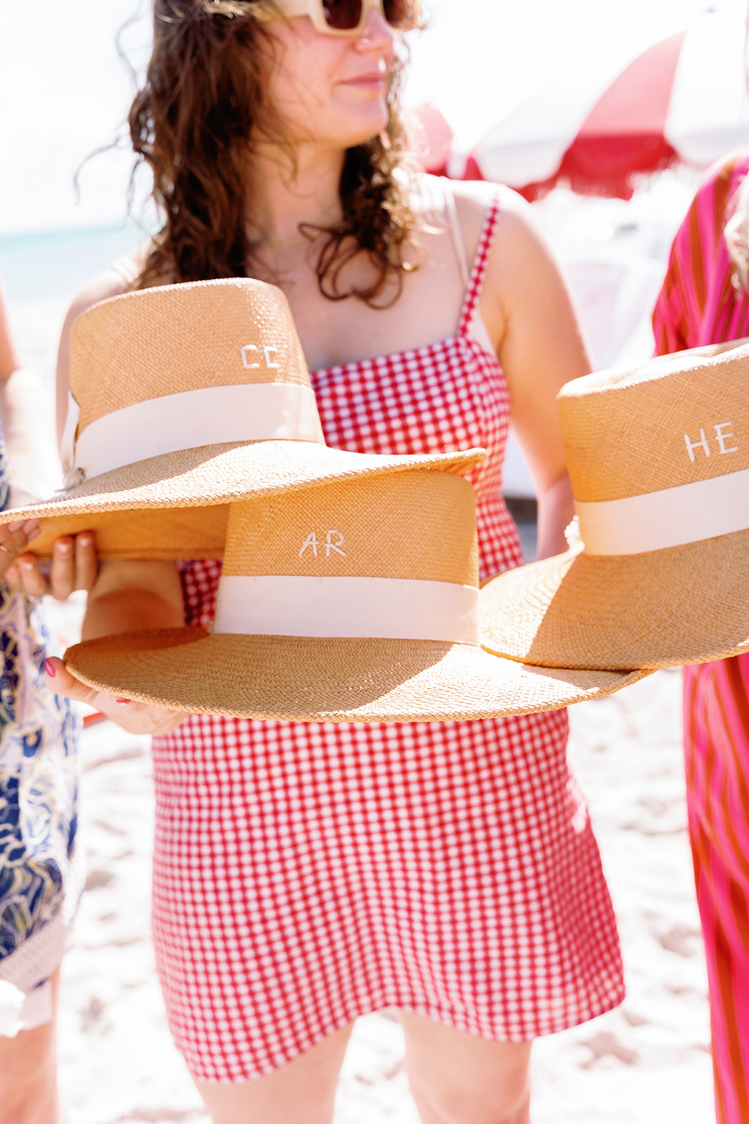 Personalized straw hats displayed during a beach wedding welcome party