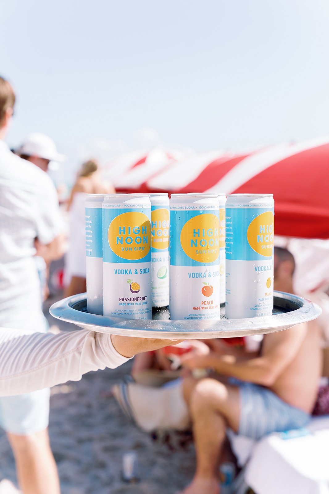 Tray of canned drinks being served to guests during a beach wedding welcome party